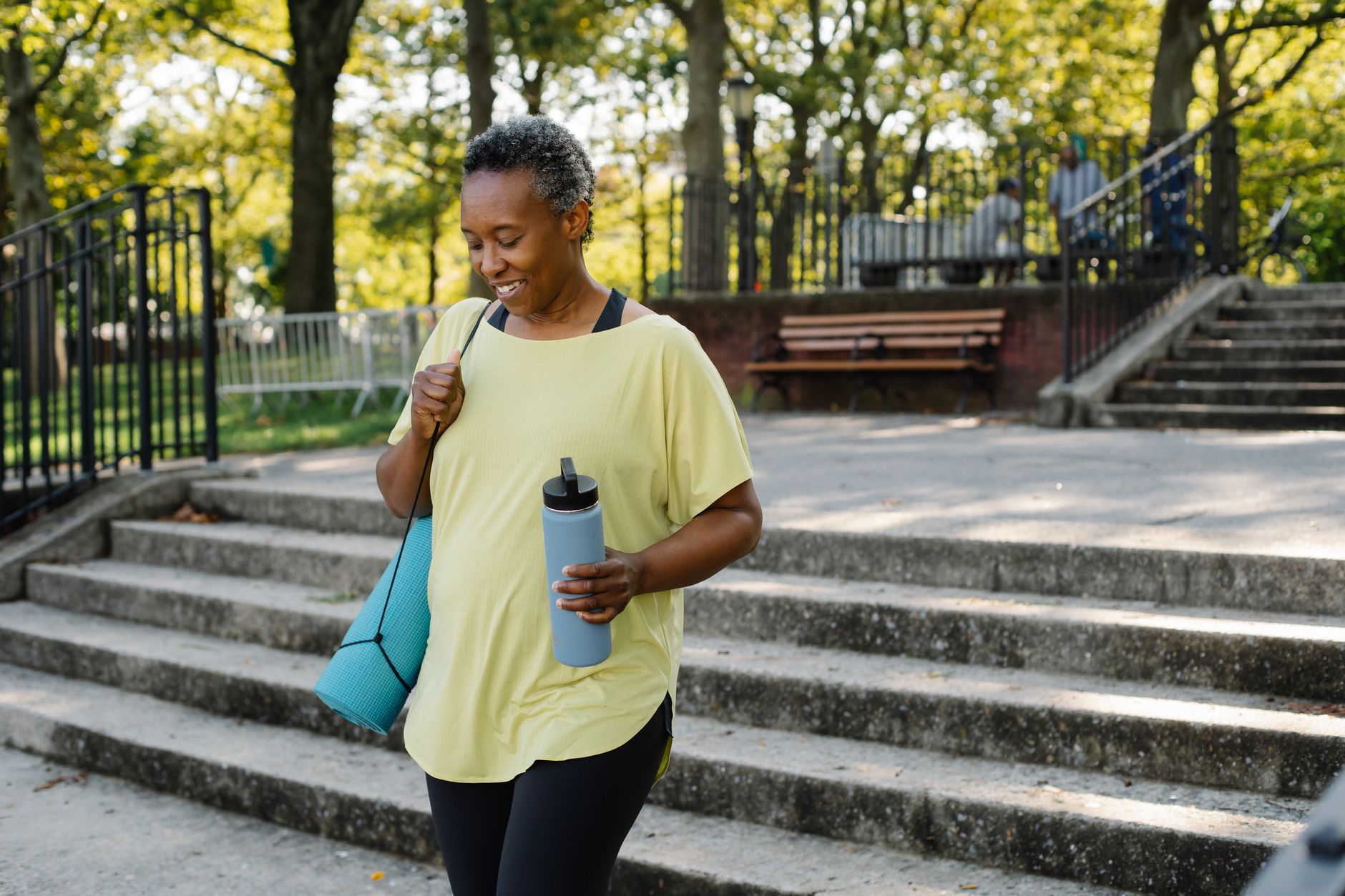 pregnant person walking outdoors in a park with a water bottle