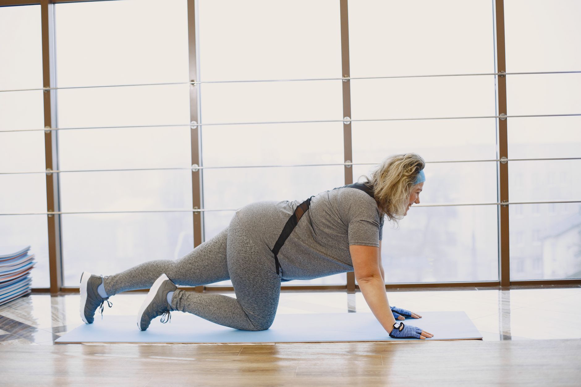 a pregnant woman in comfortable workout clothes performing a low-impact step exercise in a bright, airy home gym, demonstrating a safer alternative to jumping jacks during pregnancy