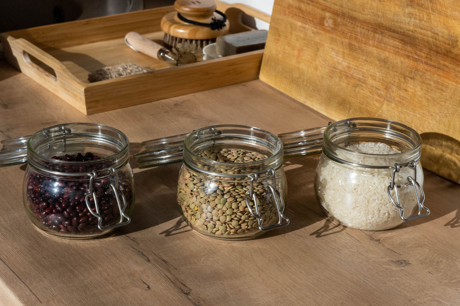 A glass jar of homemade kefir on a wooden countertop, with a spoonful of kefir grains visible, soft natural lighting