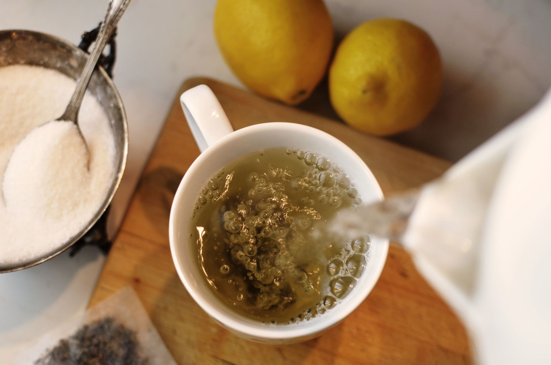 a selection of herbal tea bags on a kitchen counter, including licorice root, ginger, peppermint, and rooibos, with a steaming mug beside them