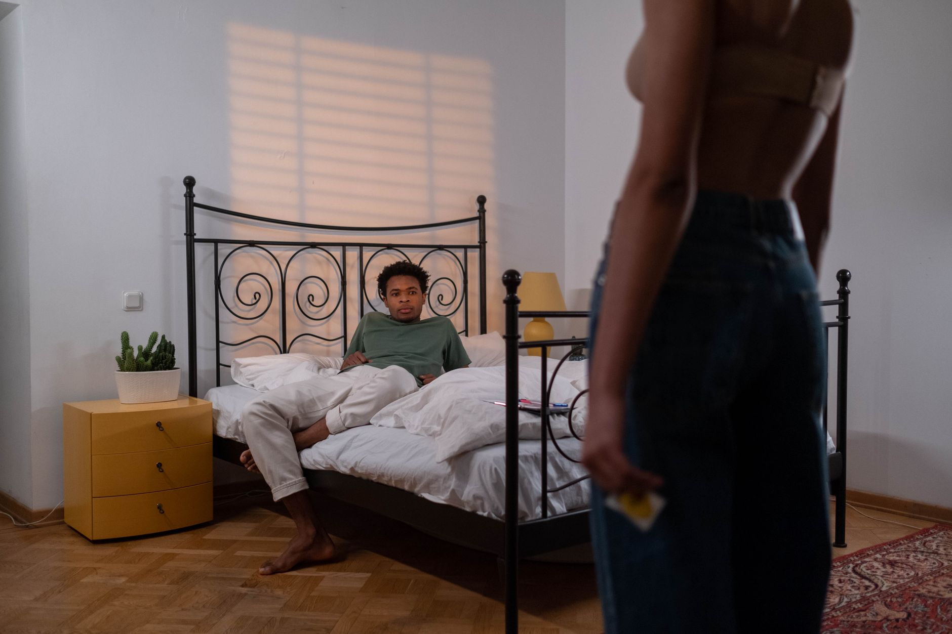 A cozy bedroom scene with a bottle of silicone lubricant placed beside a closed condom box, soft lighting emphasizing intimacy and safety