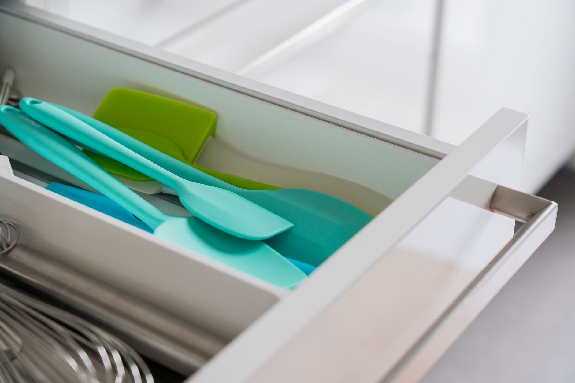 A refrigerator shelf with a sealed jar of mayonnaise, a small bowl of fresh fruit, and a reusable silicone spatula, demonstrating proper storage for pregnant individuals