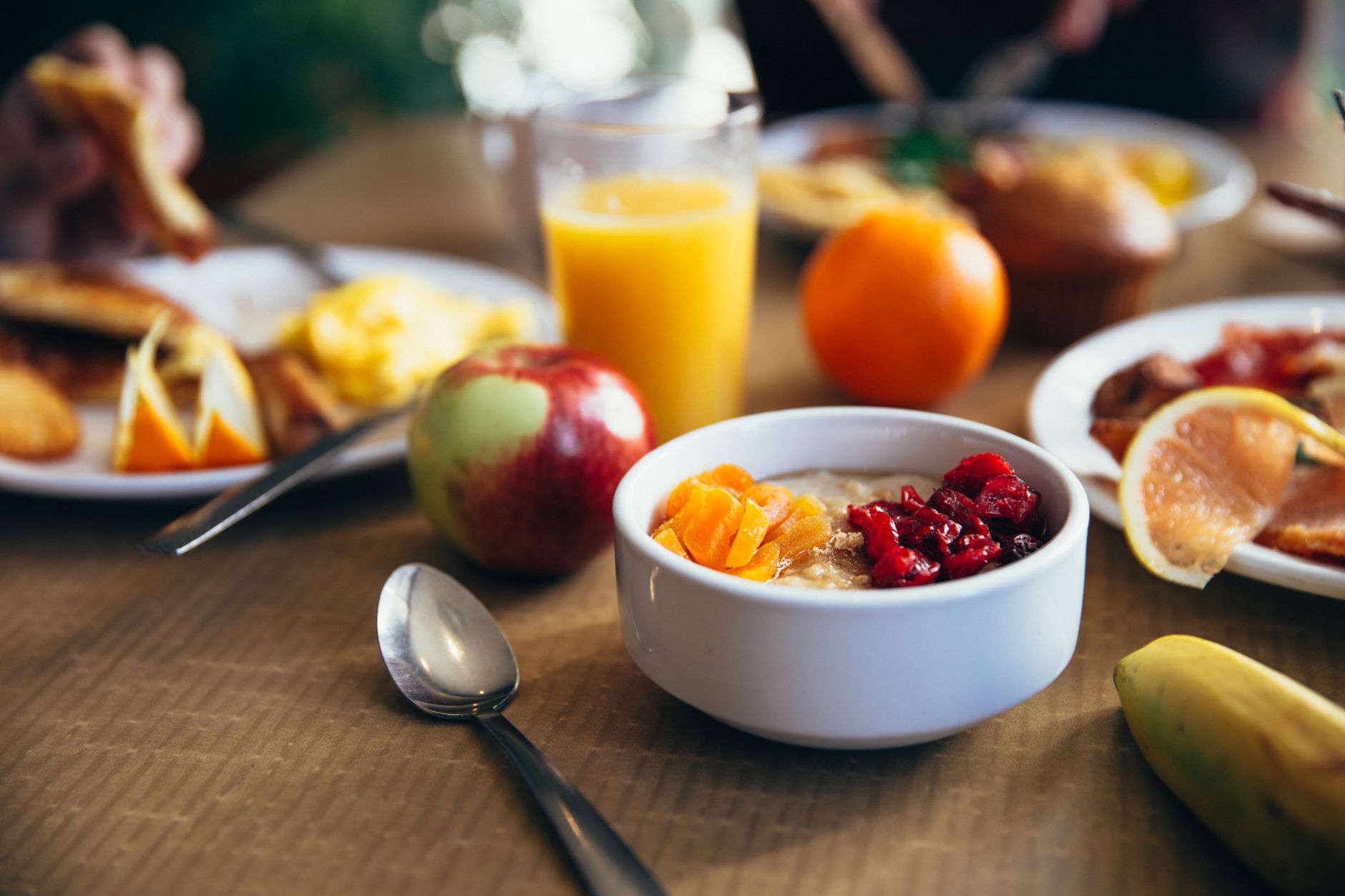 A bowl of oatmeal topped with fresh berries and a side of apple slices, illustrating a whole‑food fiber source for pregnant women