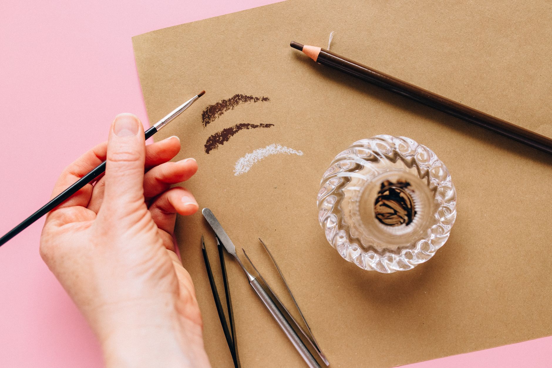 A close‑up of a pregnant woman’s hand holding a clean eyebrow pencil, highlighting a safe, non‑invasive alternative to microblading for expectant mothers