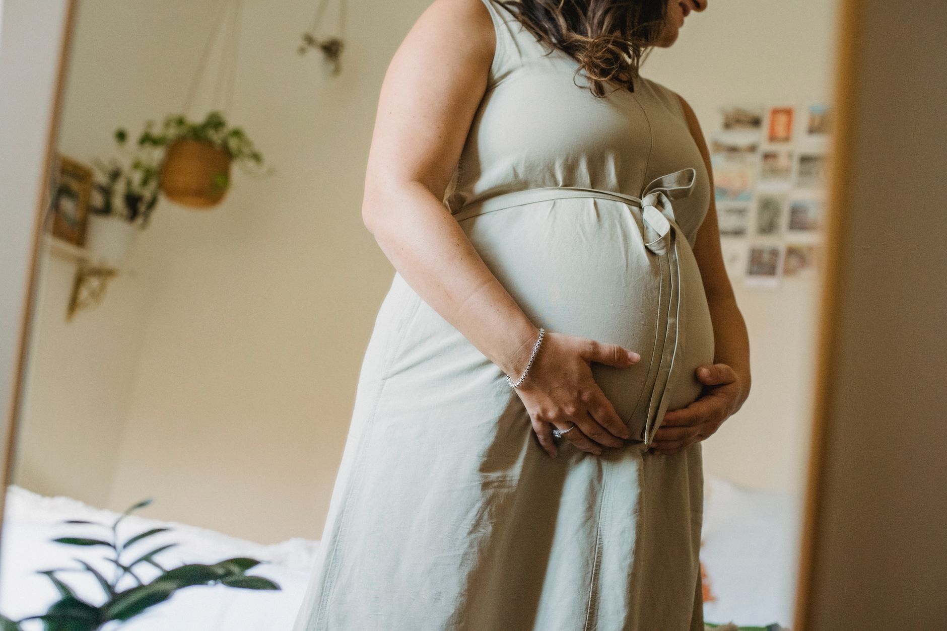 a pregnant dancer in a bright studio, wearing supportive shoes, holding a water bottle, with a wall-mounted mirror reflecting her gentle movement