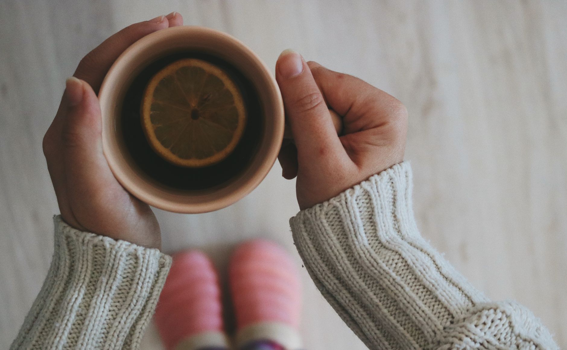 pregnant woman holding a cup of ginger tea with a slice of lemon on the side