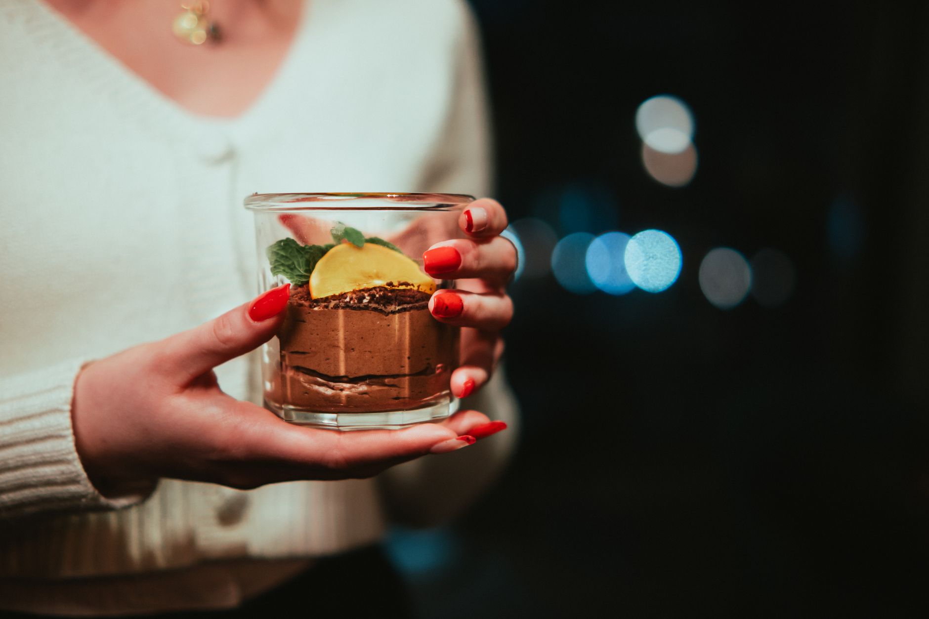 a smooth chocolate mousse in a glass bowl, topped with a sprig of mint and a dusting of cocoa powder, captured in soft natural light