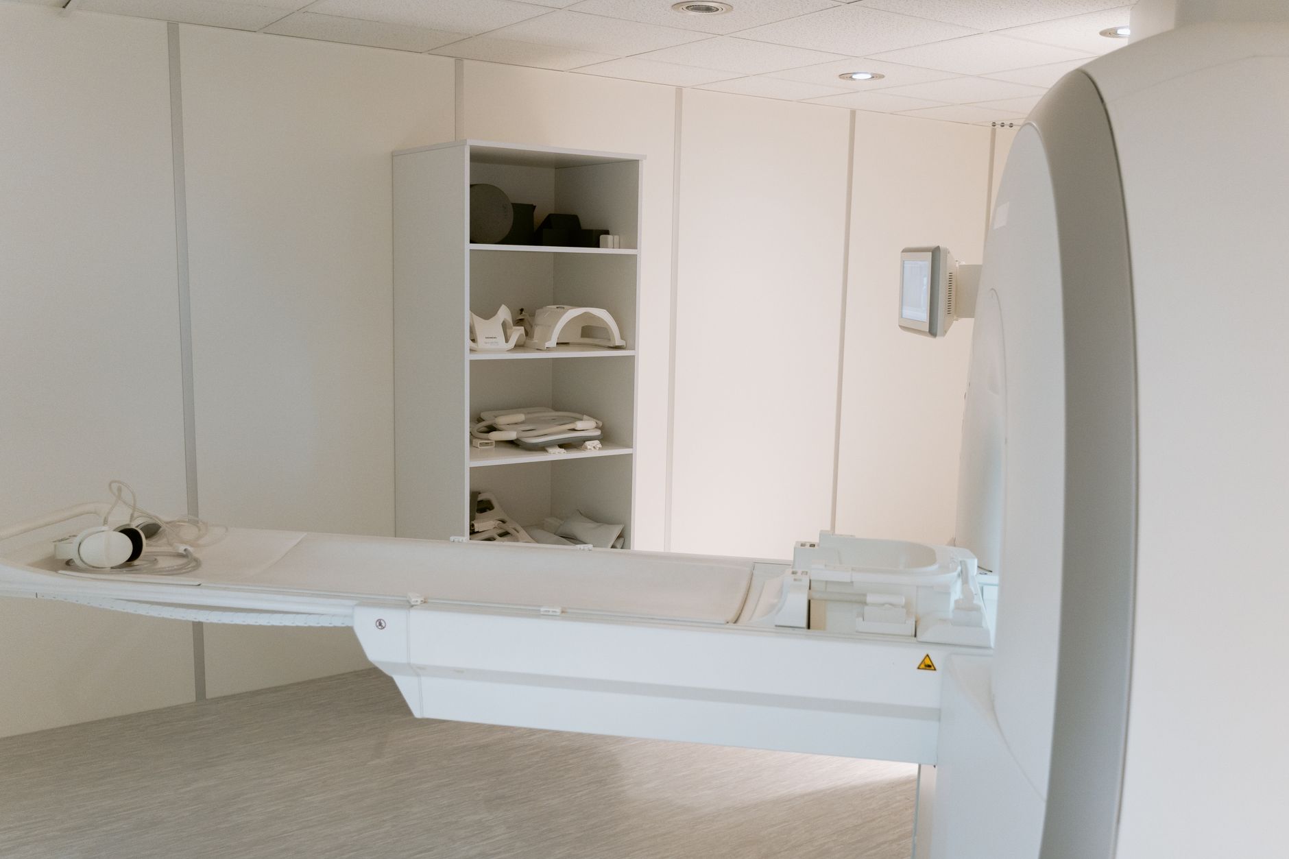 A radiology suite with a comfortable MRI table, soft blankets, ear protection devices, and a visible ultrasound machine in the background, illustrating the range of safe imaging options for pregnant patients
