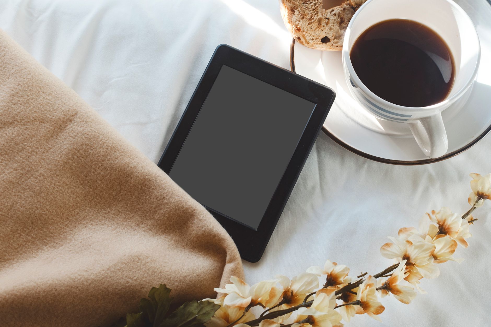 Pregnant woman holding a mug of tea while reviewing her ultrasound report on a tablet, soft morning light through a window