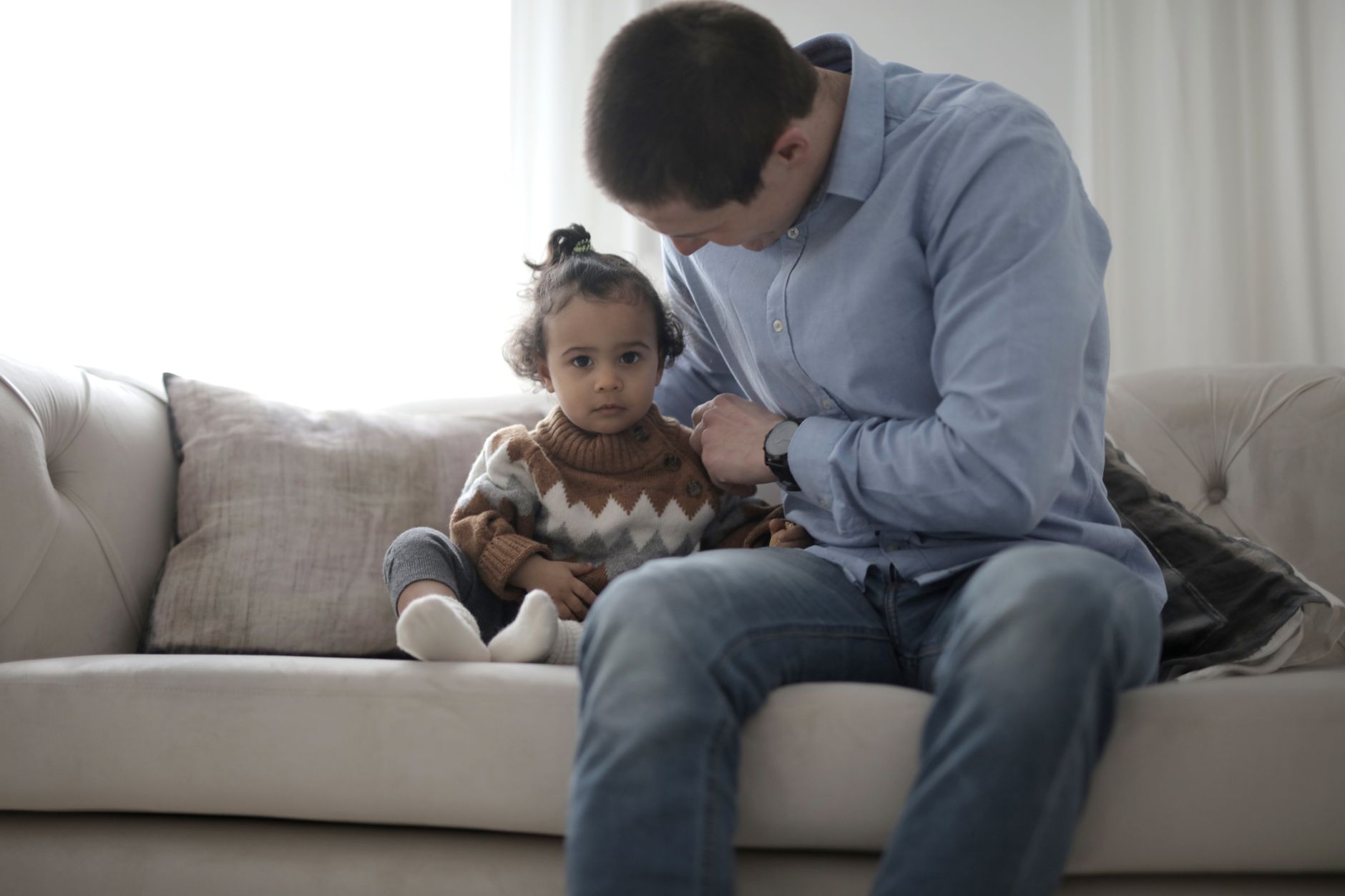 A parent gently holding their child with special needs, observing their facial expressions and movements in a calm home setting
