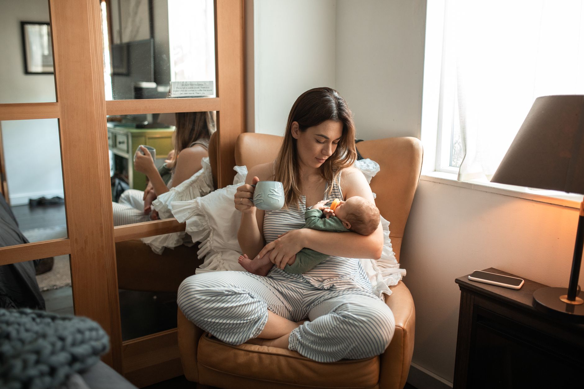A mother gently nursing her newborn in a softly lit nursery, illustrating attentive feeding and bonding