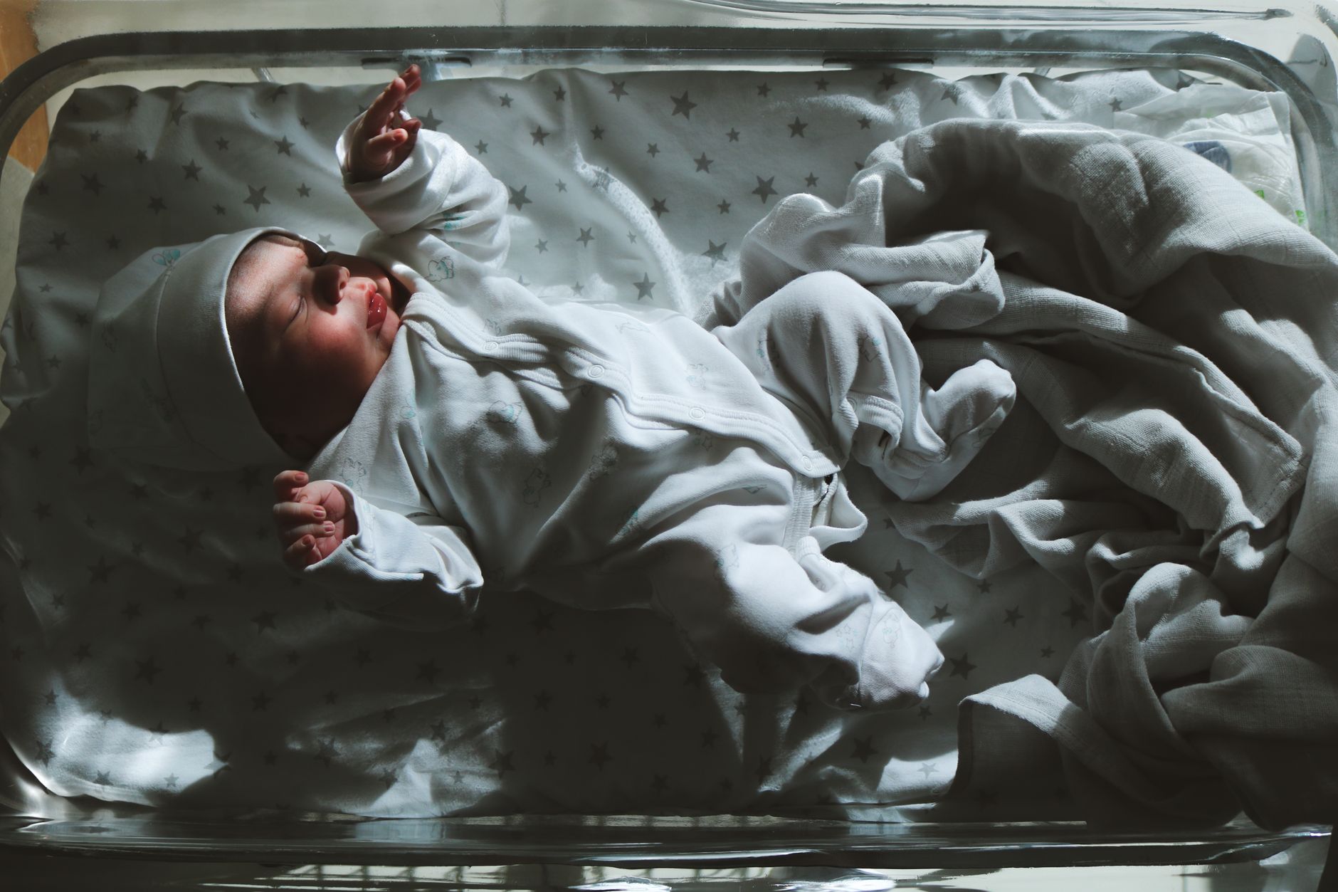 Soft‑focused image of a newborn lying under a phototherapy blanket, gentle blue light glimmering, cozy nursery setting