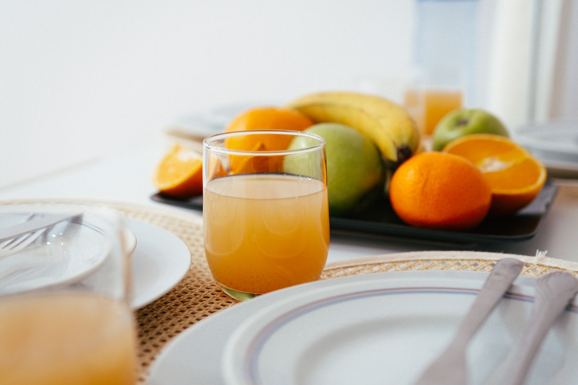 A close‑up of a labeled N‑acetylcysteine tablet beside a glass of orange juice, bright kitchen lighting emphasizing the supplement’s packaging