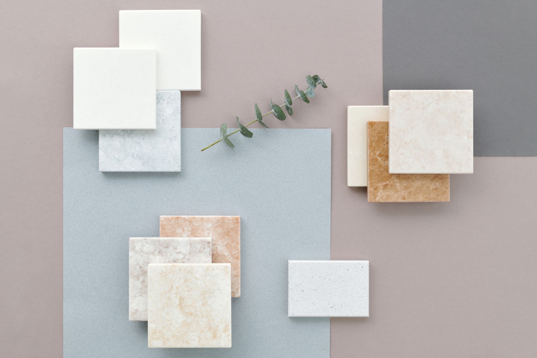 A collection of pregnancy-safe flooring options laid out side by side: a plank of hardwood, a tile sample, a roll of jute rug, a cork flooring sample, a low-VOC vinyl plank, and a VOC detector measuring air quality