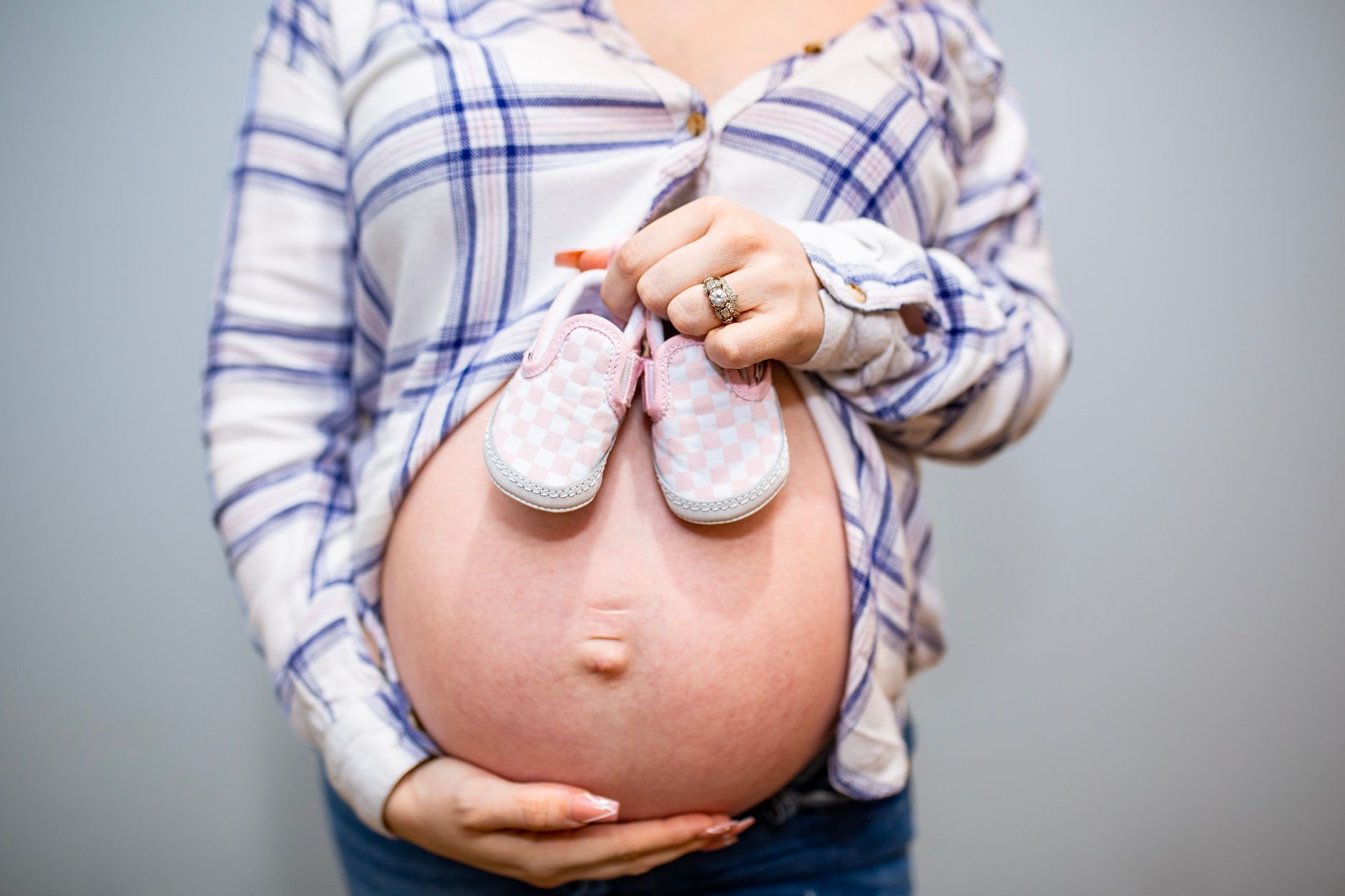A pregnant woman's hand holding a bottle of an oral rehydration solution, with a blurred background of a living room.