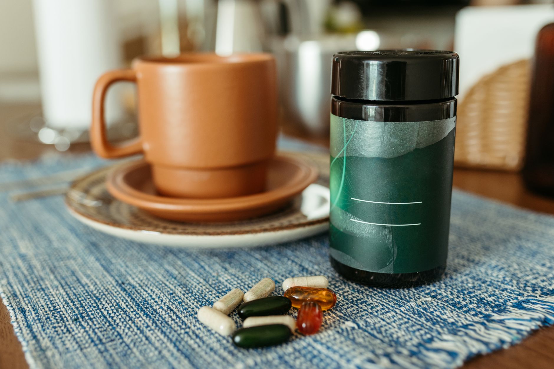 A bedside tray with a ginger capsule bottle, a cup of peppermint tea, and a bottle of prenatal vitamins, bathed in soft morning light