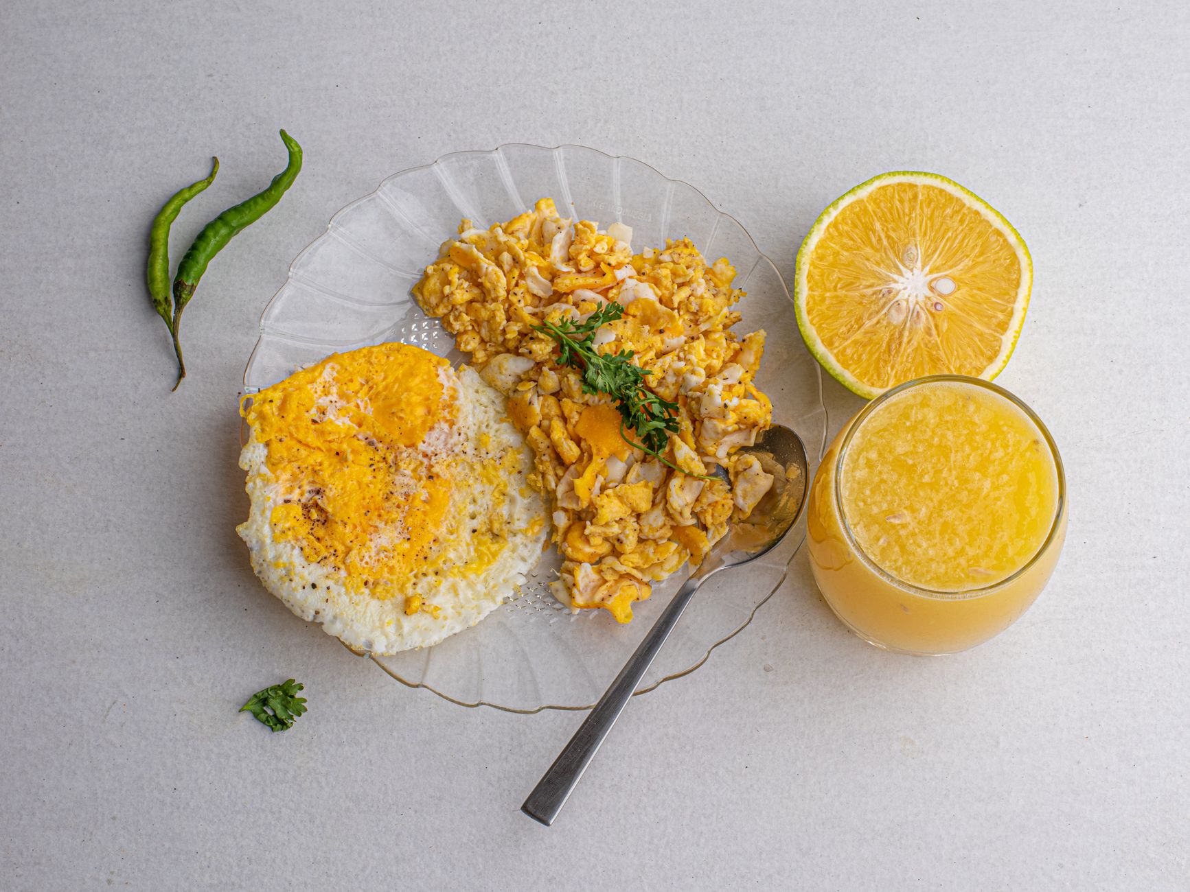 pan of scrambled eggs fully cooked, fluffy texture, bright morning light, kitchen countertop with a glass of orange juice