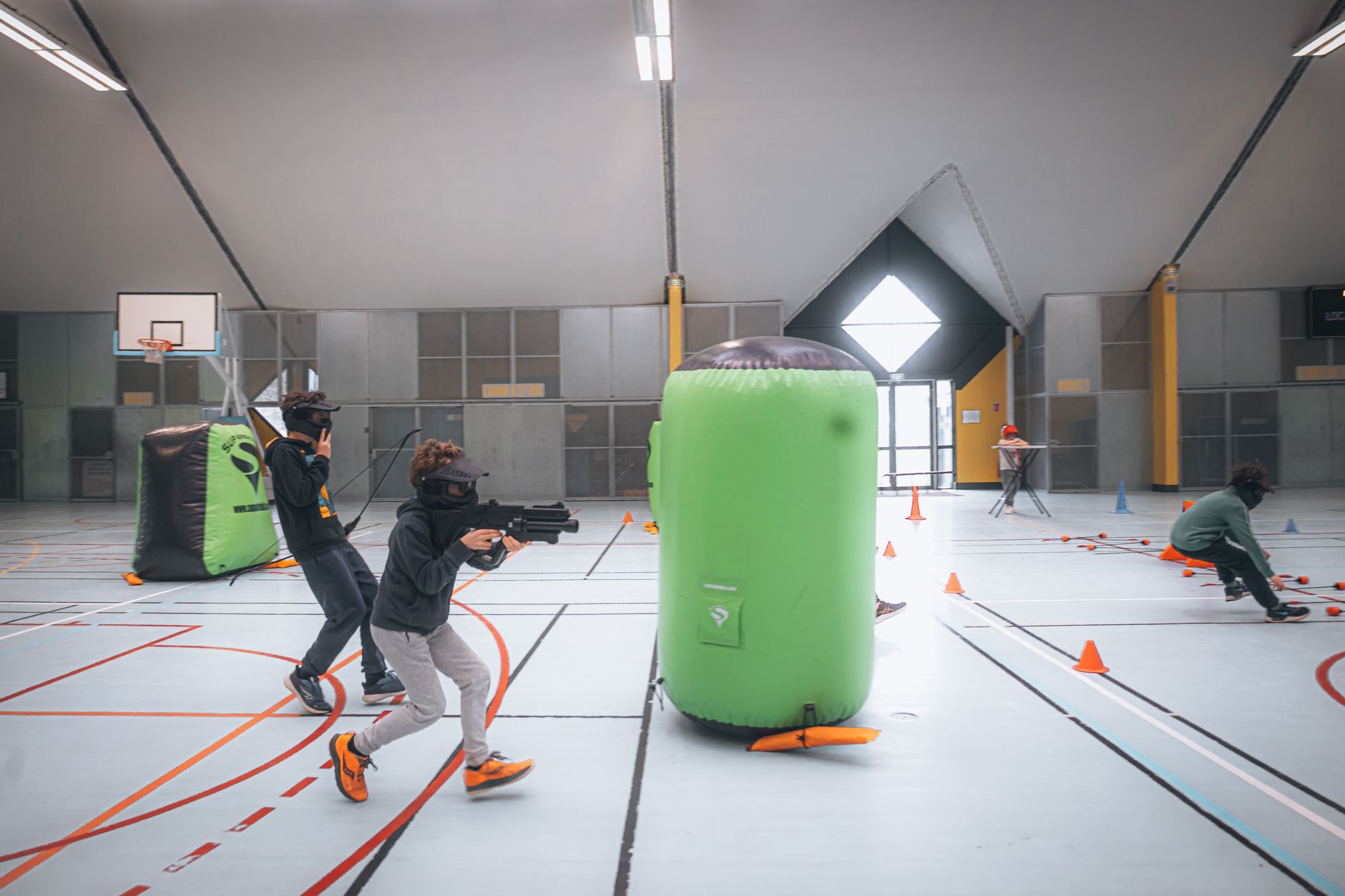 Laser tag arena with soft lighting and a pregnant woman holding a laser gun, smiling