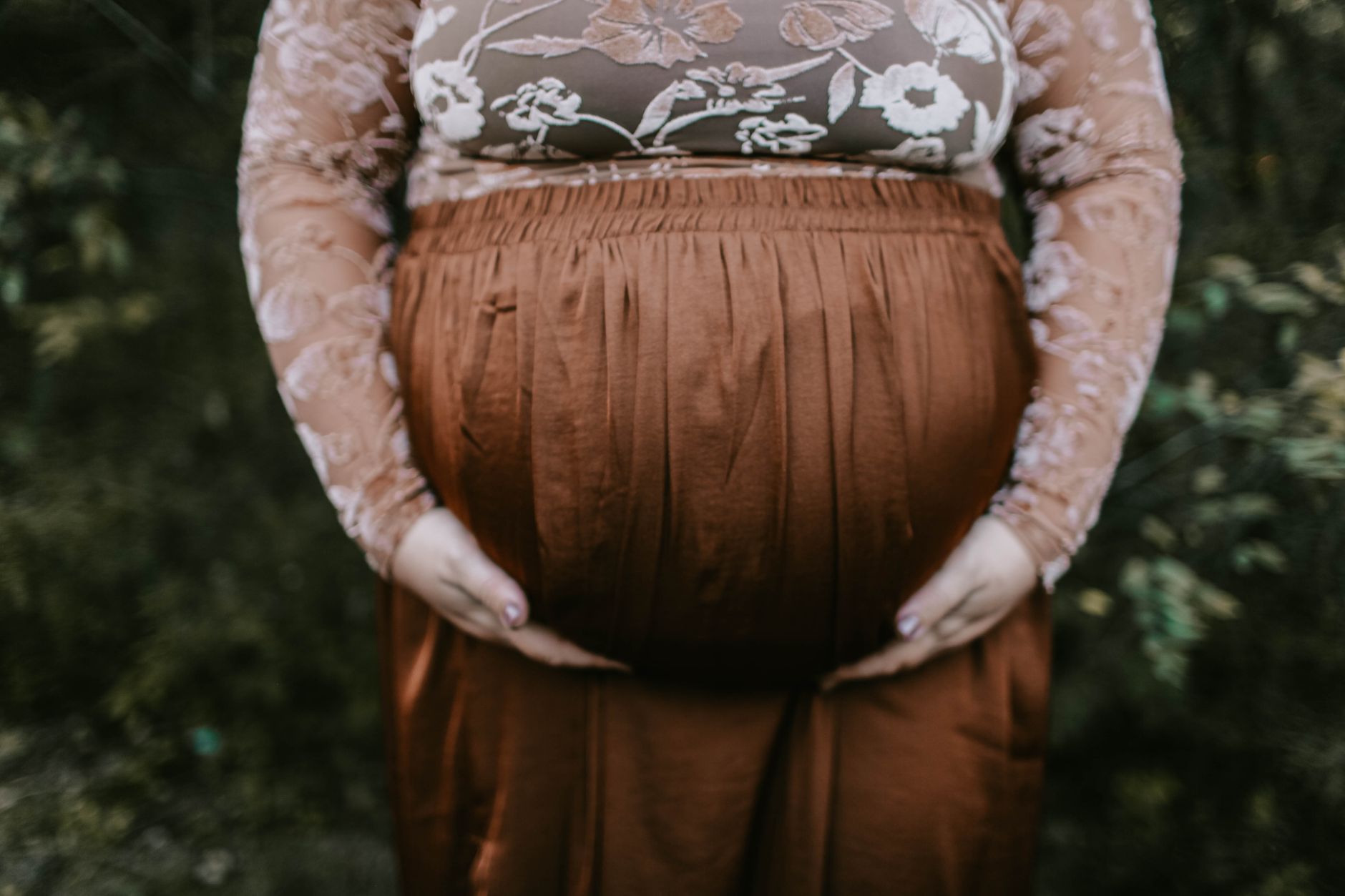 a pregnant woman using a supportive maternity belt while walking in a park, soft daylight, comfortable clothing