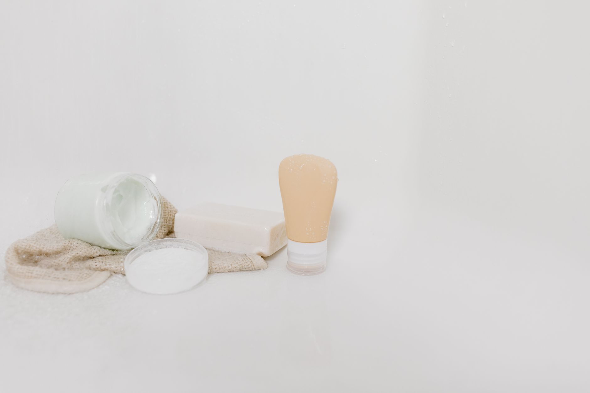 a tidy bathroom shelf with pregnancy‑safe hair products, a glass bottle of gentle curl cream, and a soft pink towel, natural daylight