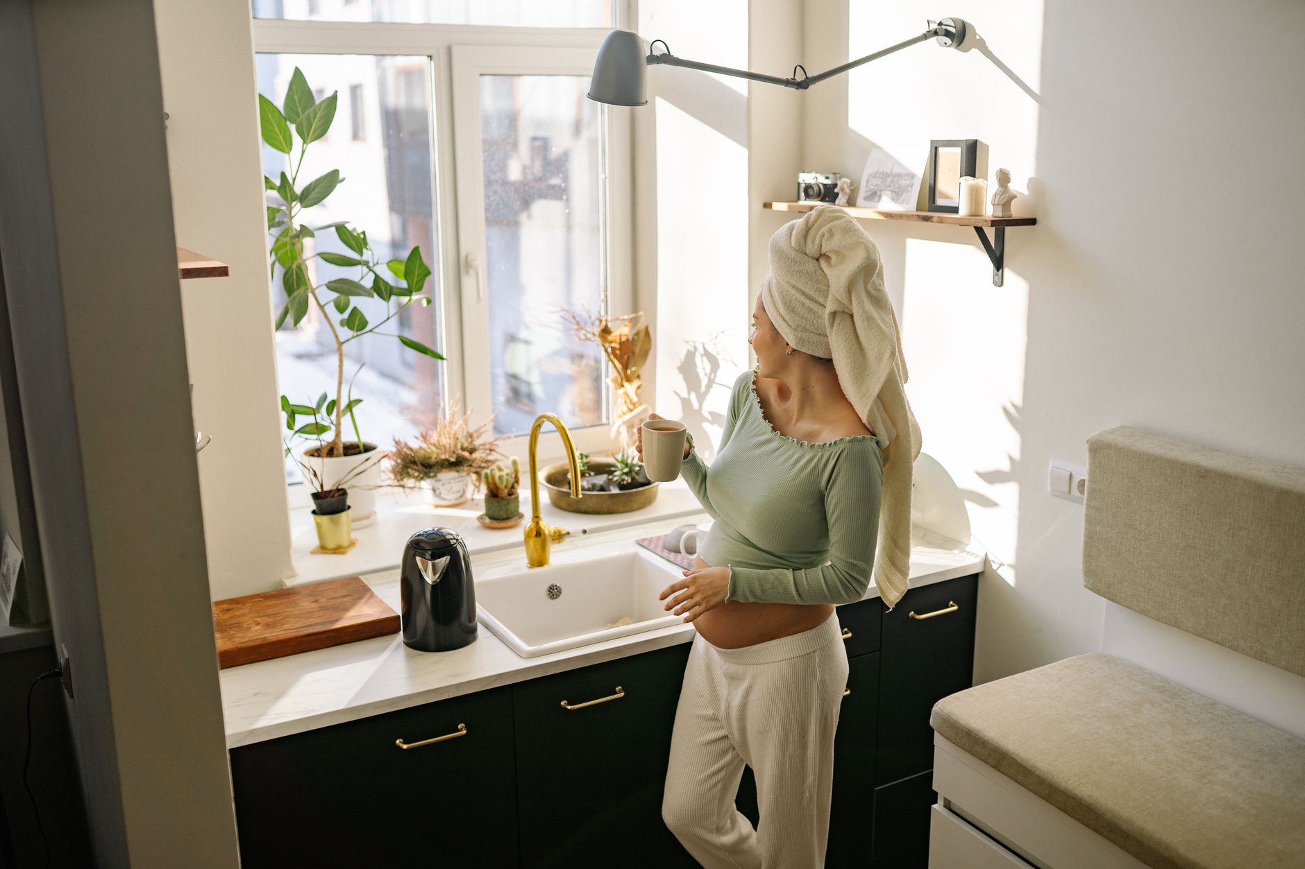 a cozy kitchen scene with a pregnant person holding a glass of non‑alcoholic hibiscus tea, soft natural light highlighting the deep red hue of the tea, a gentle reminder that flavorful, safe drinks are available
