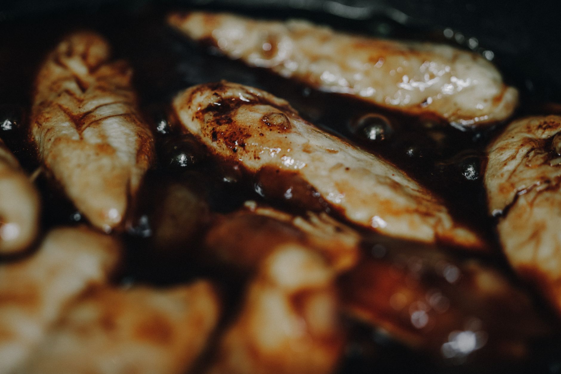 A skillet with a thin slice of prosciutto sizzling, steam rising, illustrating how a quick sear can reduce bacterial risk for pregnant individuals.
