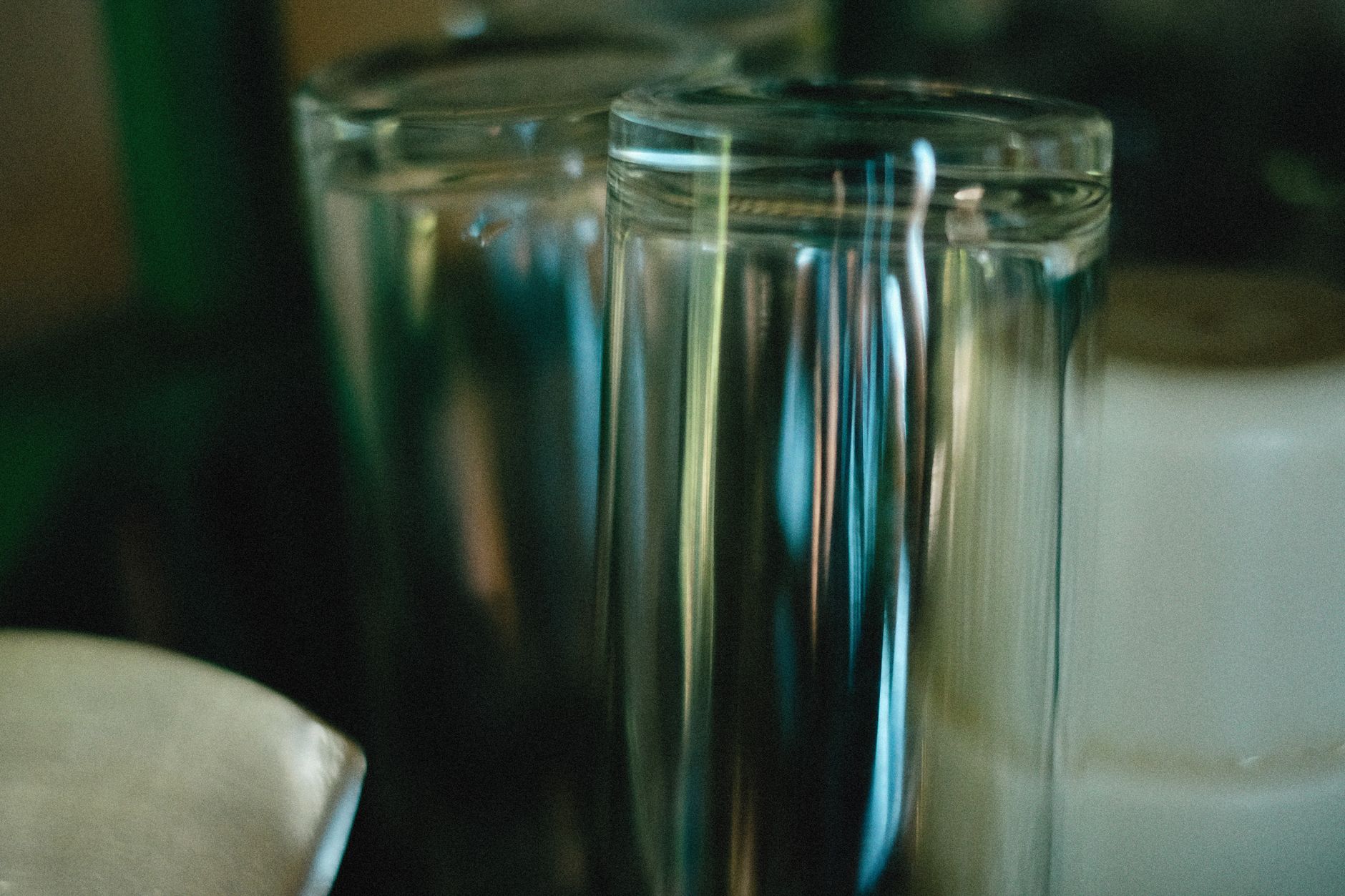 close‑up of a clear protein drink bottle on a nightstand with a baby onesie and a glass of water, soft ambient lighting
