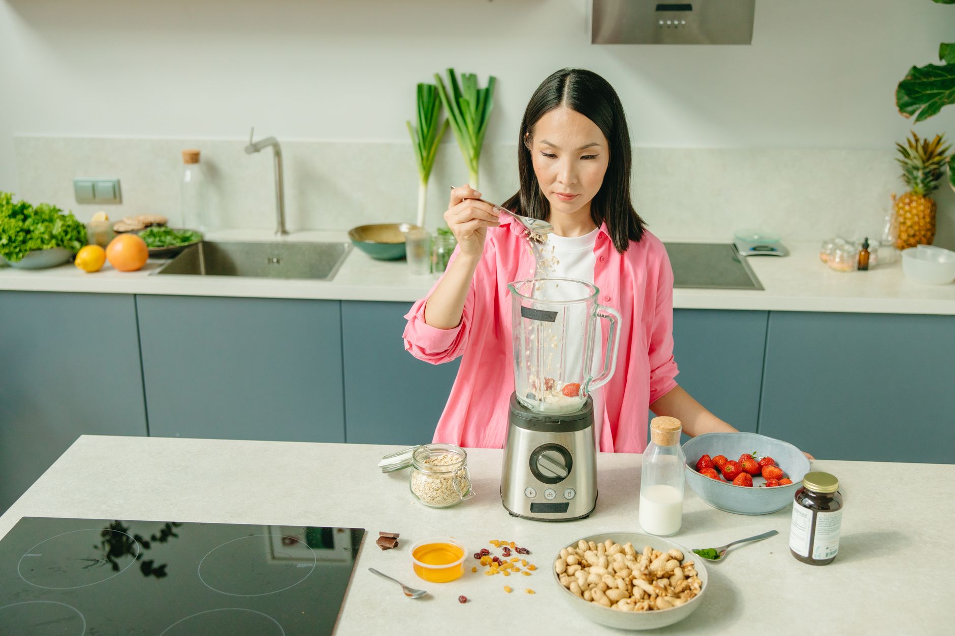 a pregnant woman stirring a protein shake into a glass of almond milk, soft morning light, kitchen counter with fresh fruit and a prenatal vitamin bottle nearby