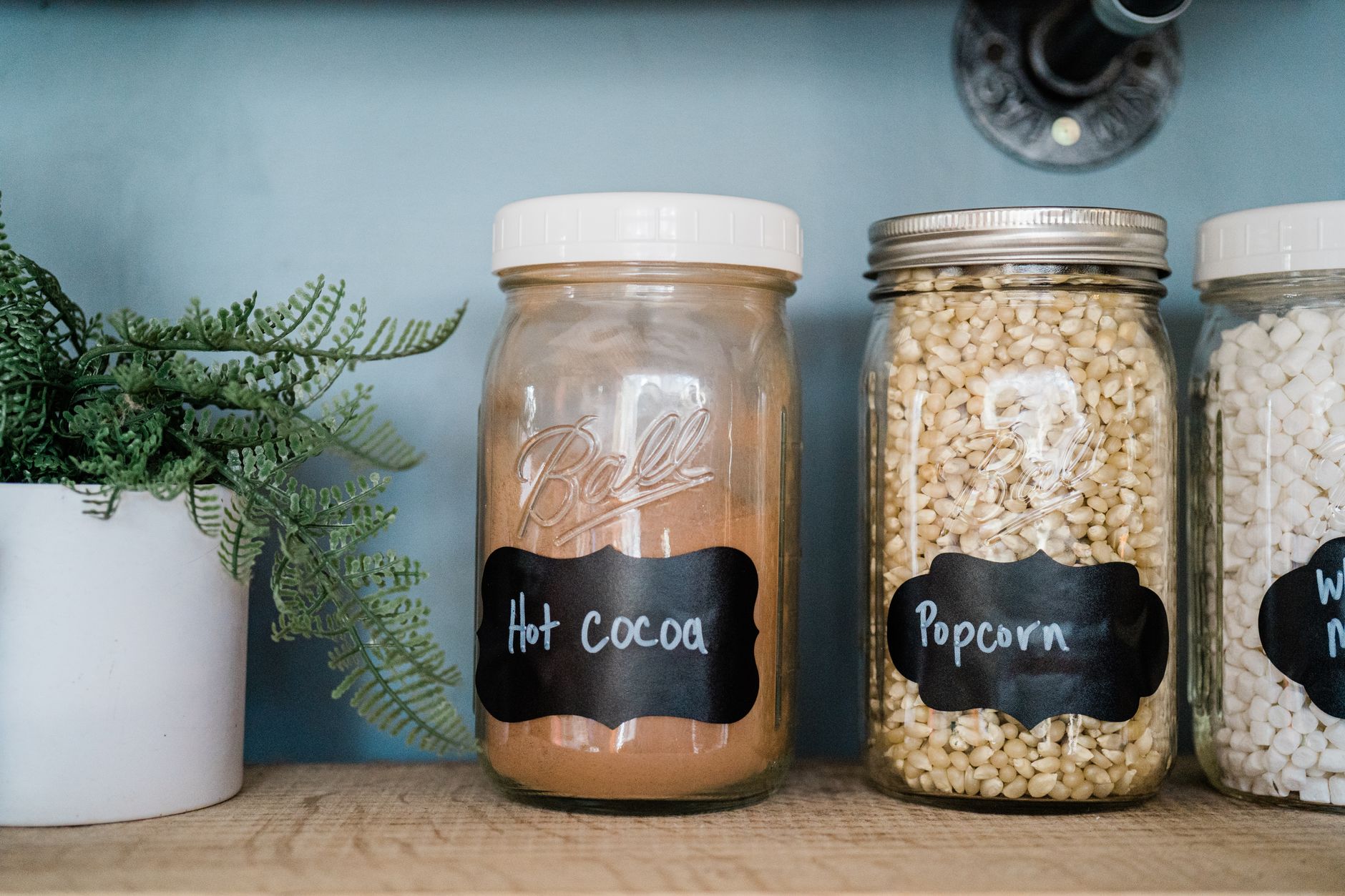 a tidy pantry shelf with a small bowl of dark chocolate almonds, a box of low‑sugar chocolate bar, and a jar of almond butter chocolate cups, soft natural light