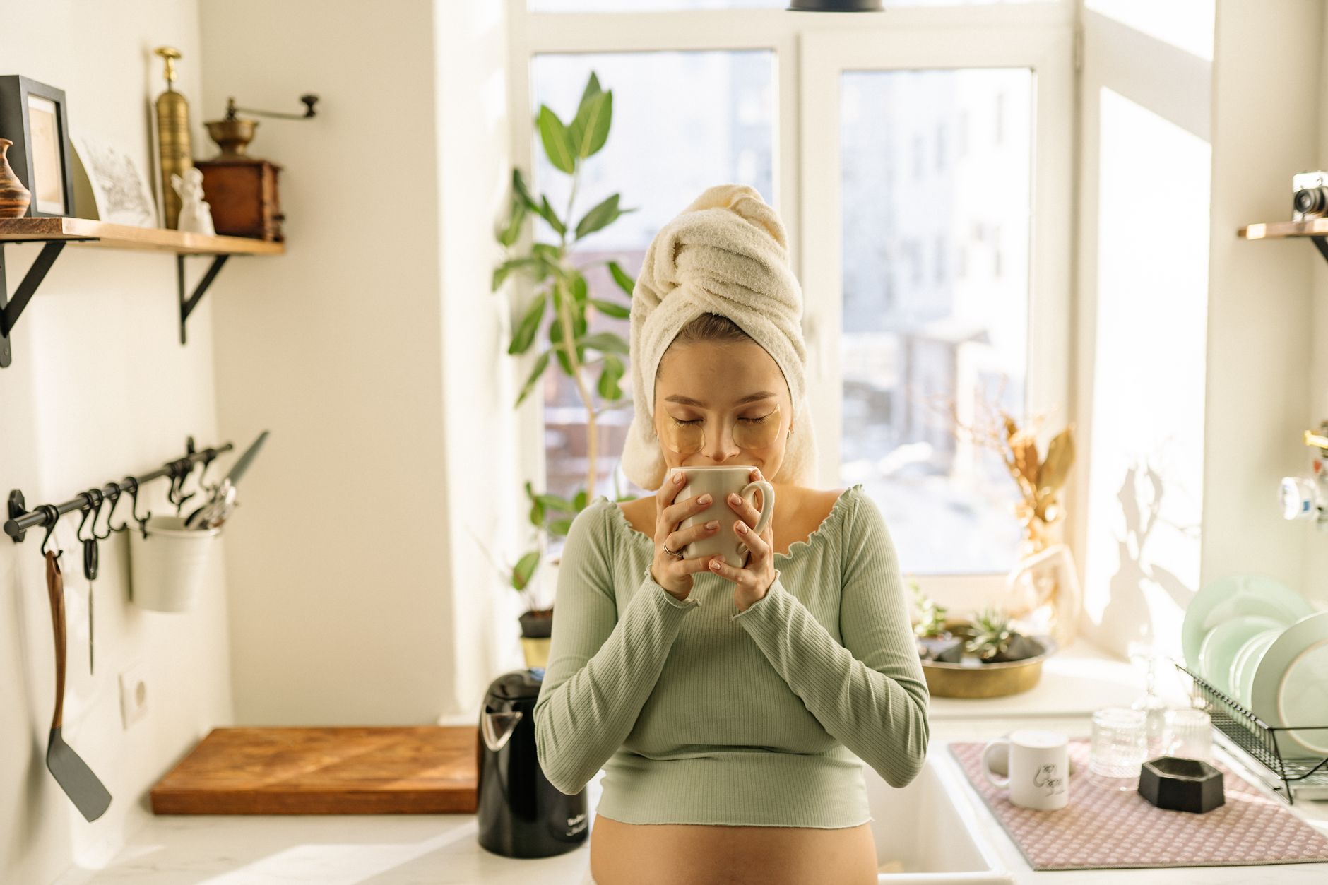 A pregnant woman holding a ginger tea mug while a reishi supplement bottle sits untouched on a nearby table, soft indoor lighting emphasizing calm and choice