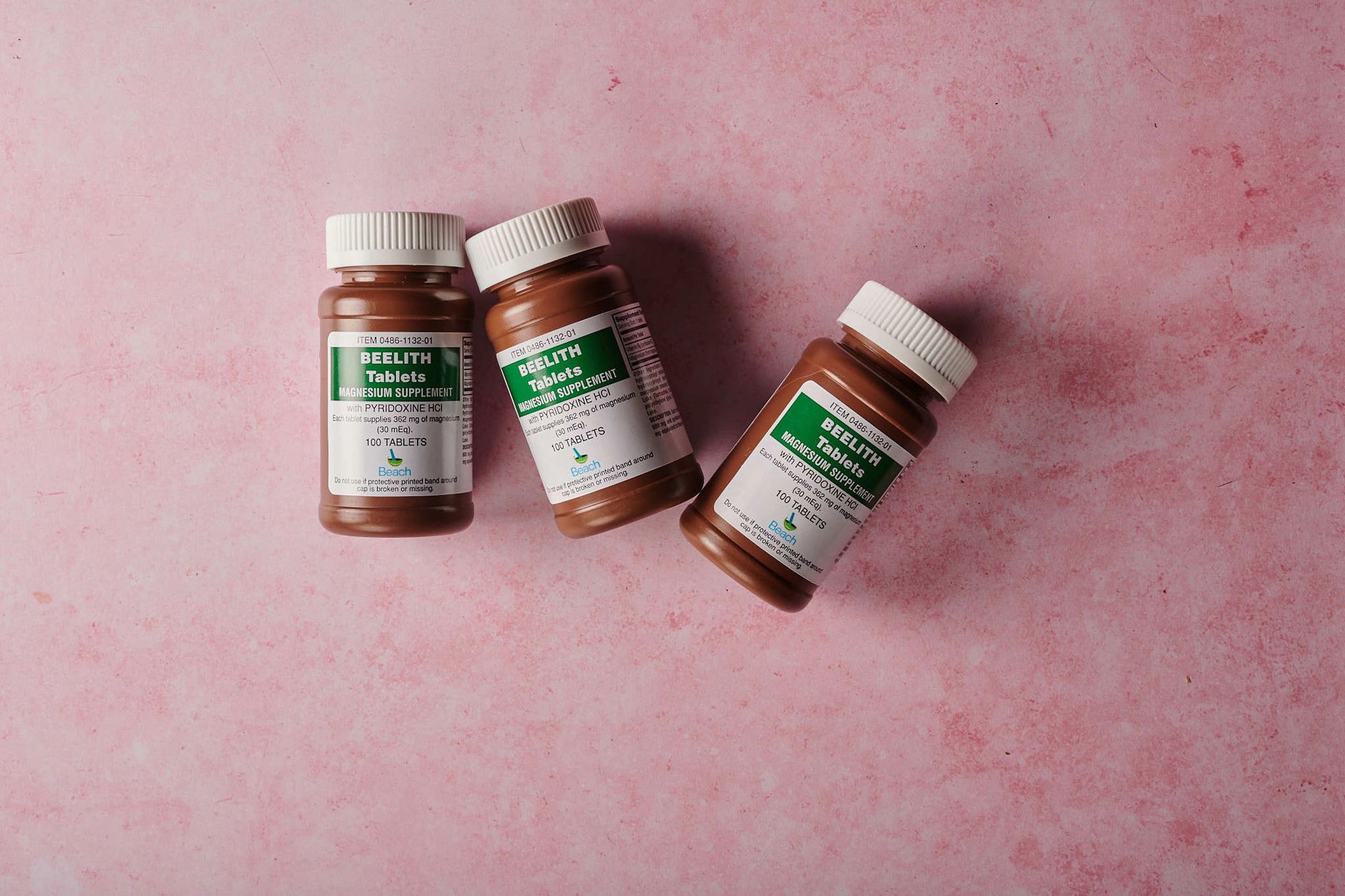 A collection of prenatal supplements and a bottle of Requip on a kitchen counter, illustrating safe medication choices for pregnant people