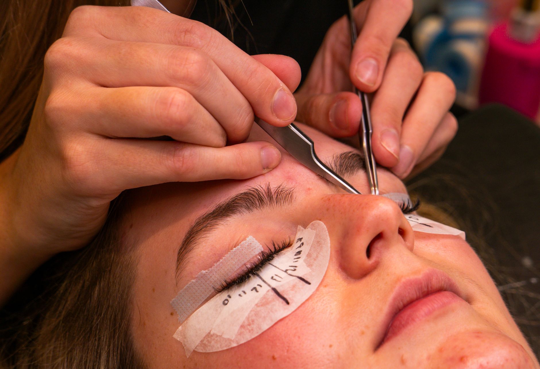 close-up of a woman gently applying lash serum along her upper lash line