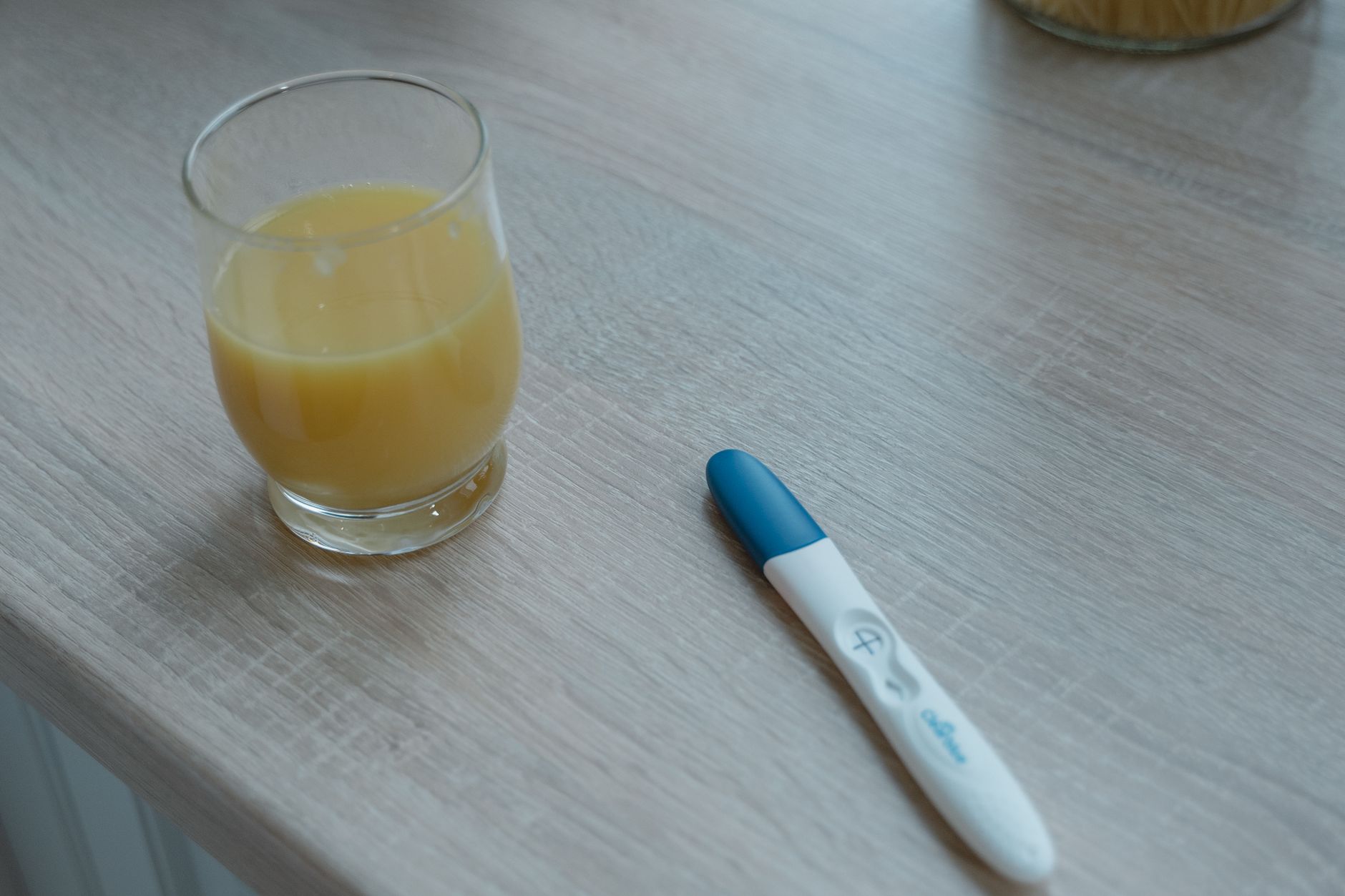 a hand holding a pregnancy test and a small bottle of enoxaparin next to a calendar, soft natural lighting, minimalistic composition