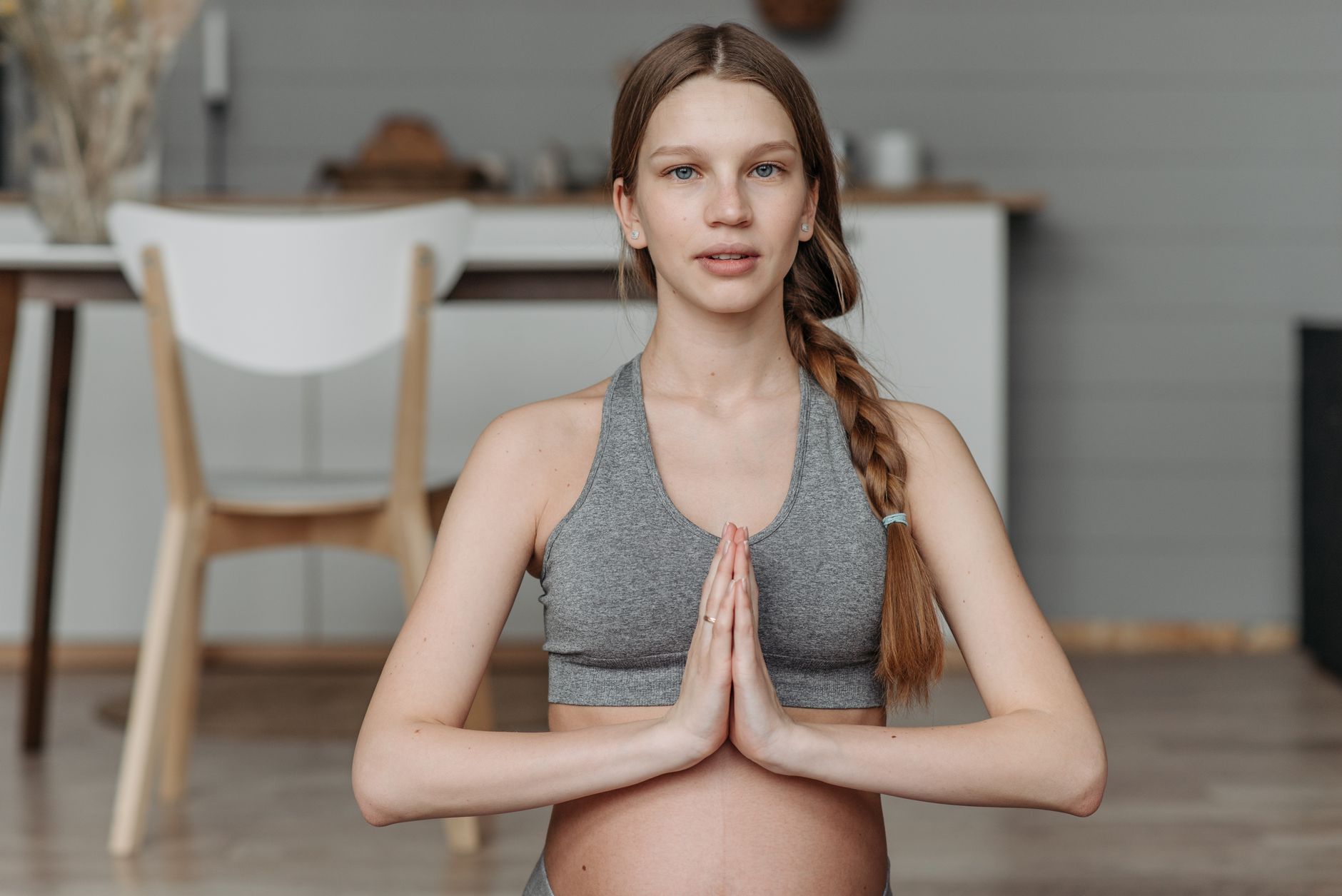 A pregnant woman doing a gentle prenatal yoga pose on a mat in a bright, airy room.