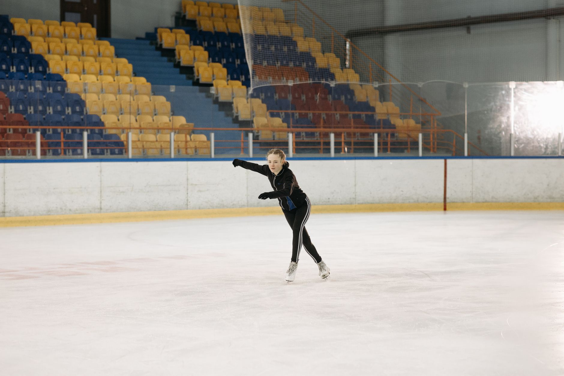 pregnant woman gently rolling on smooth indoor track with a supportive helmet and wrist guards, illustrating safe rollerblading practice for expectant mothers