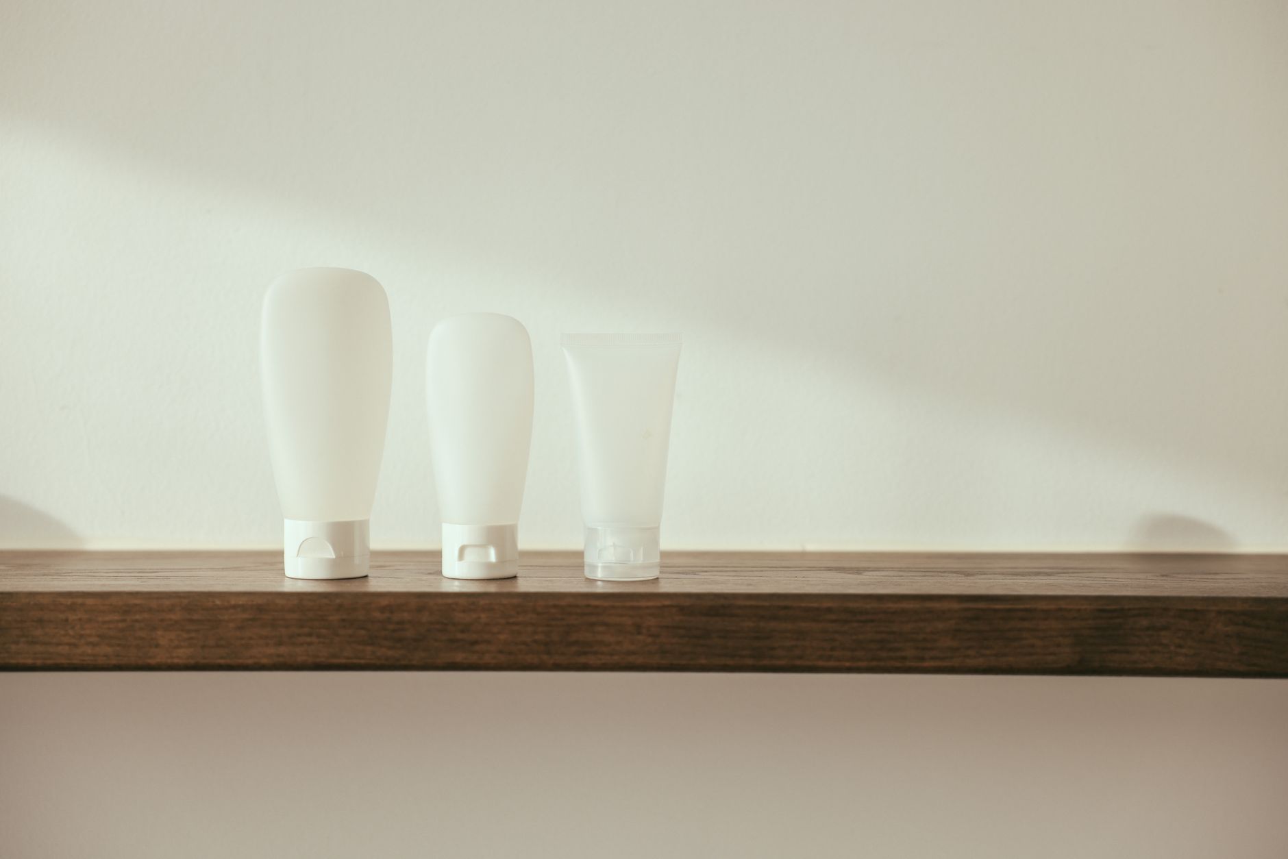 A collection of natural hair‑color alternatives, including a tin of henna powder, a bottle of vegetable‑based dye, and a tube of color‑depositing conditioner, displayed on a wooden countertop with soft daylight