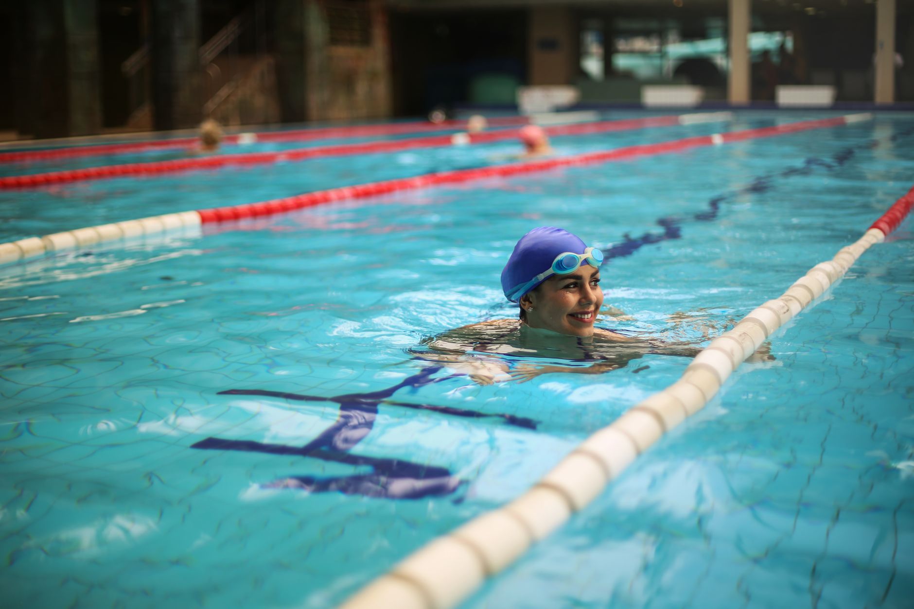 pregnant woman swimming laps in a pool, wearing a one-piece swimsuit
