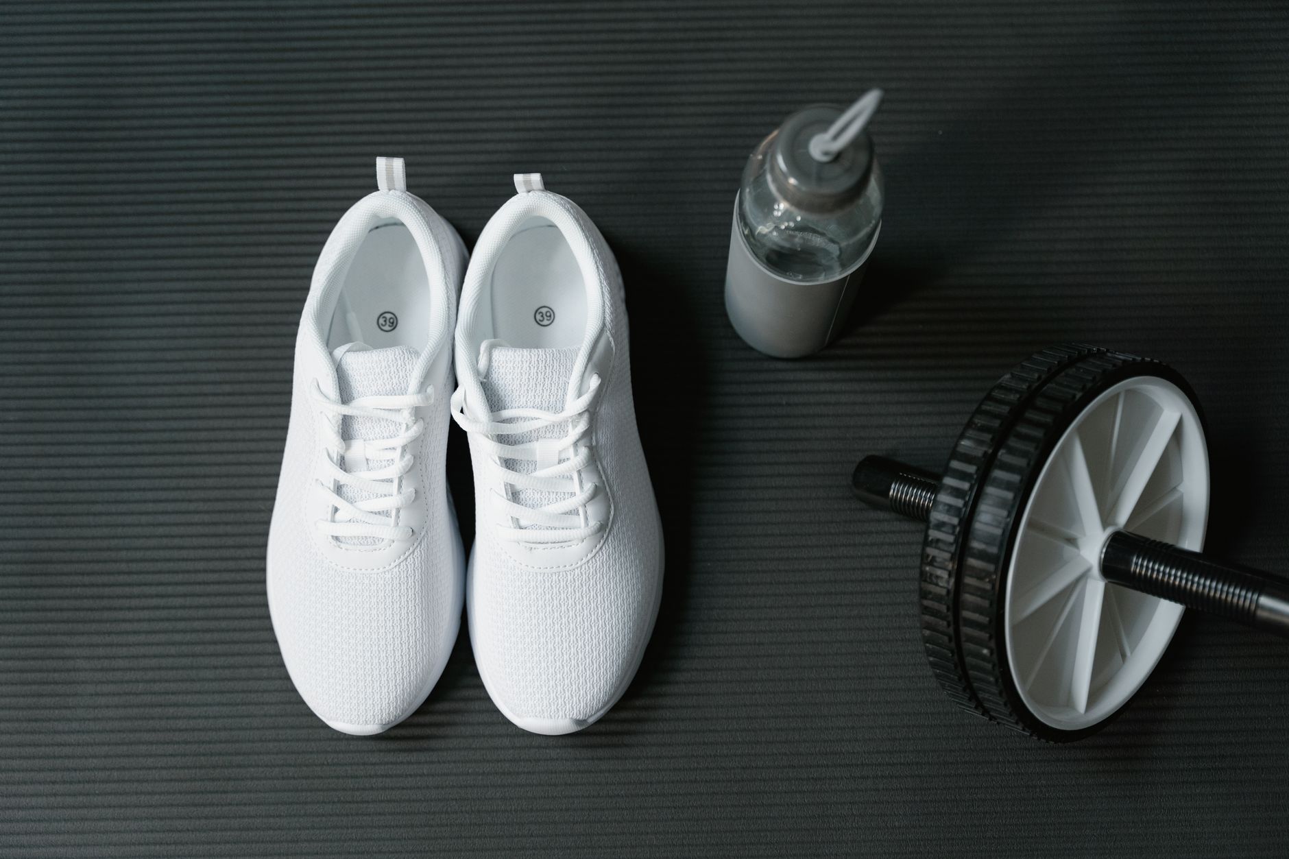 A calm indoor space with a yoga mat, a pair of running shoes, and a water bottle, illustrating a balanced workout area for pregnant exercisers