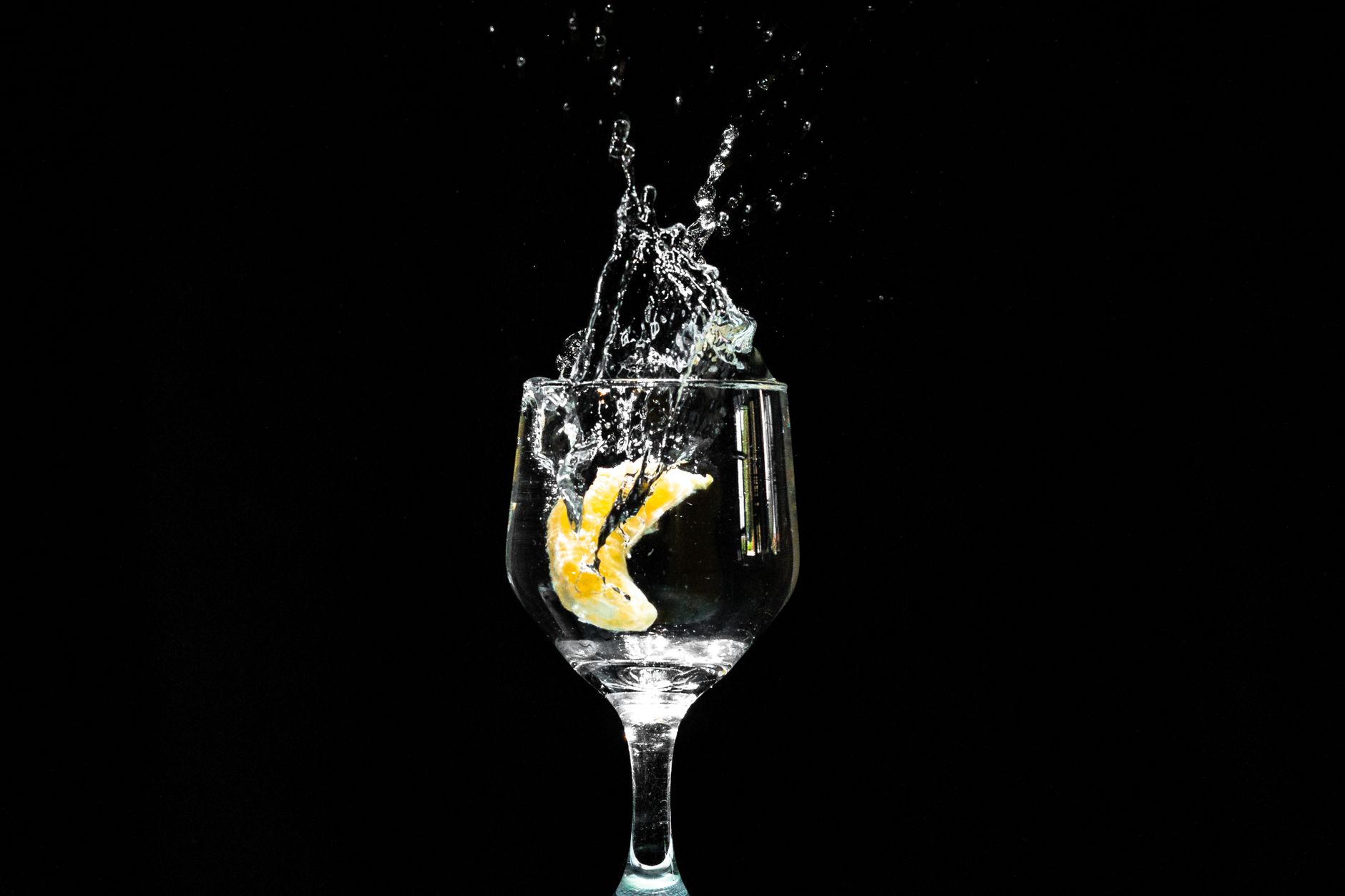 Close‑up of a white wine glass with a swirl of wine, a small sprig of rosemary, and a lemon wedge beside it