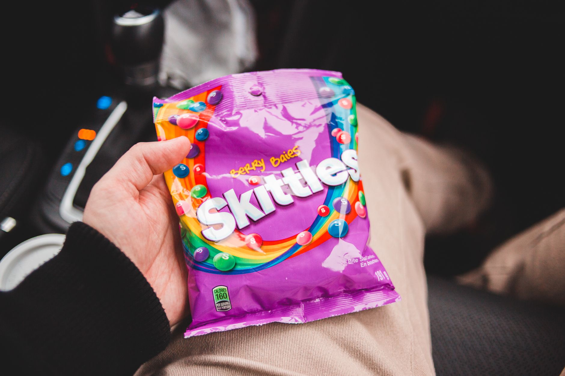 A close‑up of a Skittles packet label showing ingredients and nutrition facts, bright lighting, studio setting
