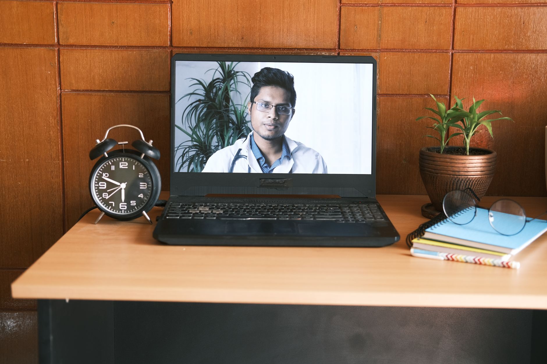 a pregnant woman sitting at a kitchen table with a notebook, discussing skydiving plans with her obstetrician over a video call, emphasizing informed decision‑making