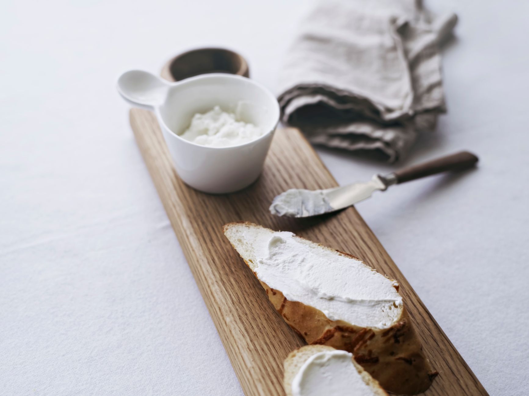 A clean kitchen countertop with a labeled container of pasteurized sour cream, a cutting board, and a small bowl ready for portioning