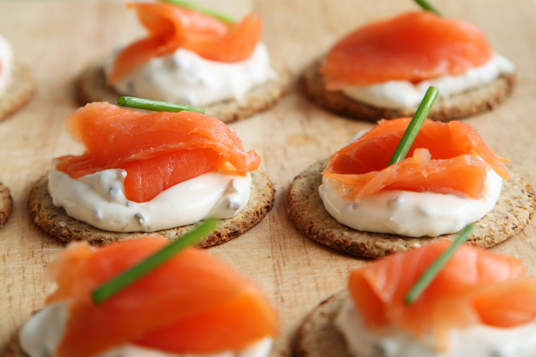 A plate of whole‑grain crackers topped with a dollop of sour cream and fresh chives, illustrating a balanced snack for pregnant cravings