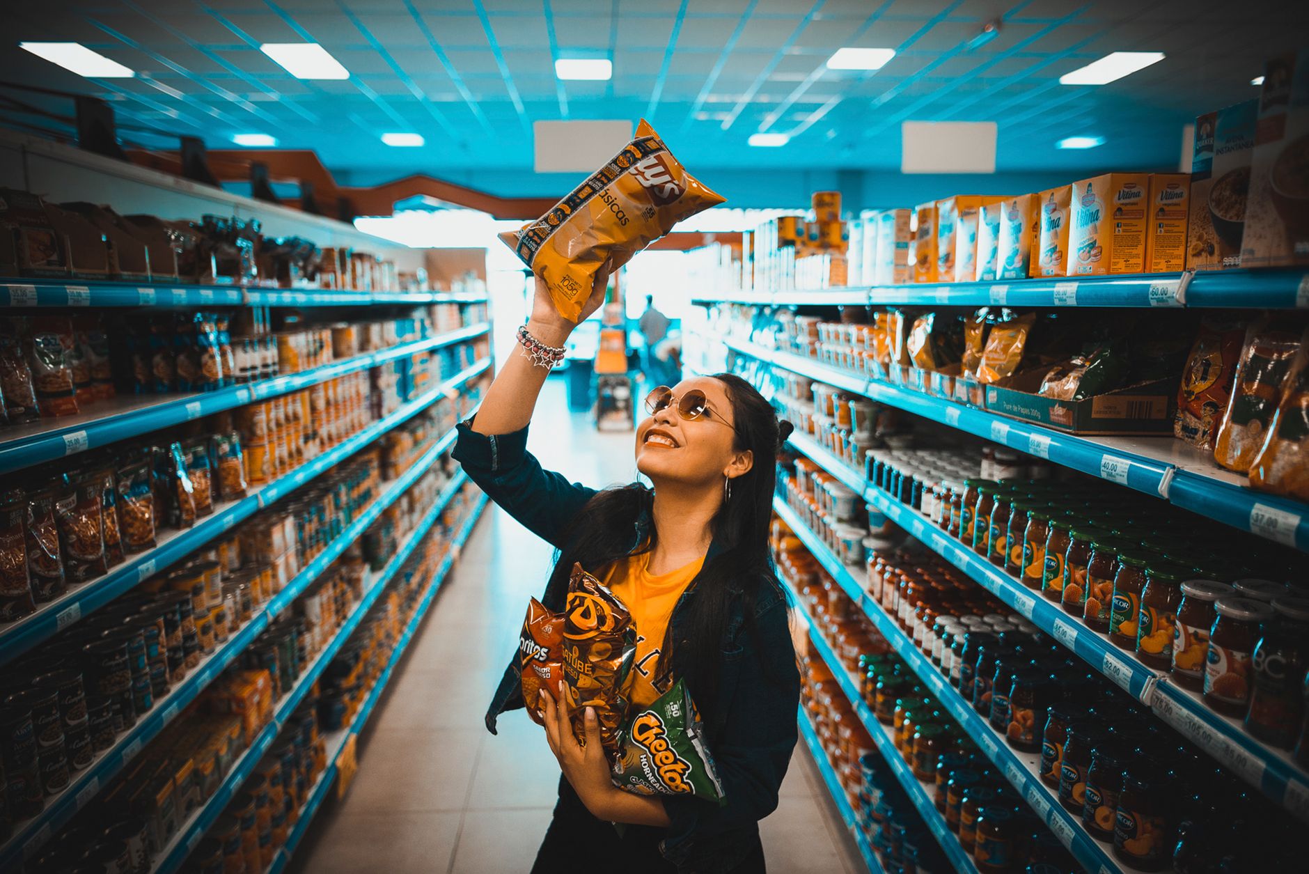 a pregnant woman holding a fun-size bag of Sour Patch Kids while grocery shopping