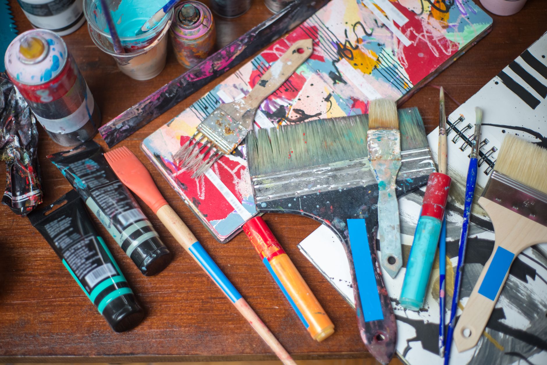 array of non‑spray painting supplies such as acrylic paint tubes, watercolor palettes, chalk paint cans, and milk‑paint jars, arranged on a sunny craft table, highlighting safer alternatives for pregnant artists