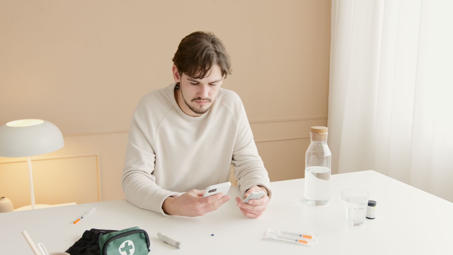 A pregnant person sitting on a couch, holding a phone with a medical alert app open, surrounded by a first-aid kit and a stethoscope, symbolizing vigilance during pregnancy