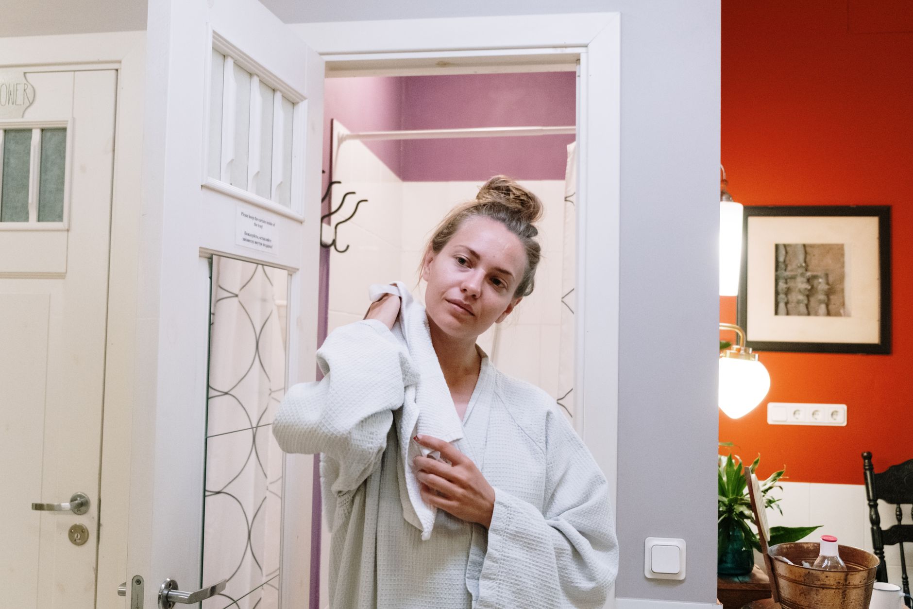 pregnant woman wrapping a towel around her shoulders after a short steam room session, smiling, with a glass of water on a nearby table – illustrating safe post‑steam hydration