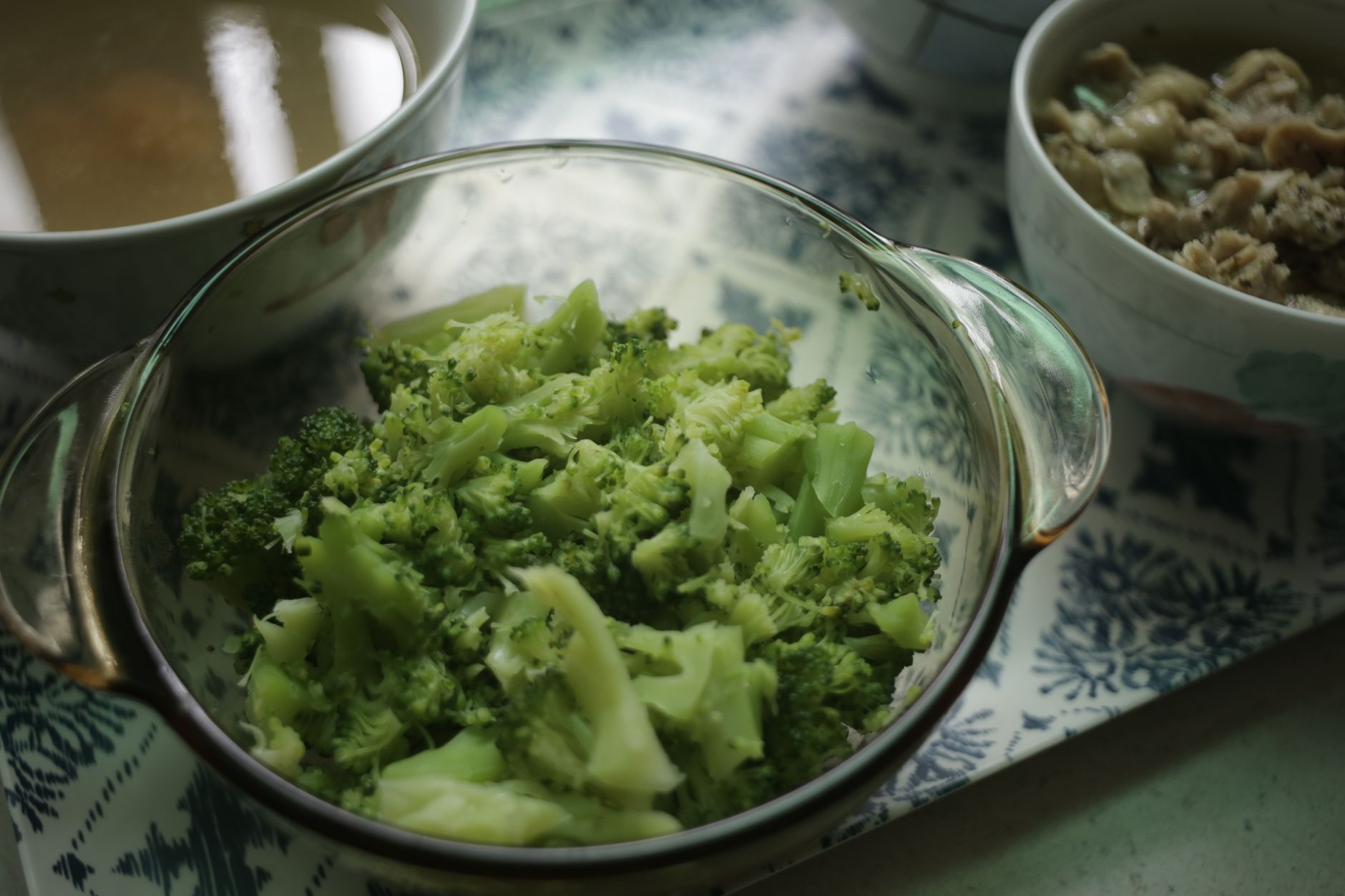 a steaming pot of broccoli florets on a stovetop, next to a bottle of prenatal vitamins, illustrating whole‑food versus supplement choices for pregnancy health