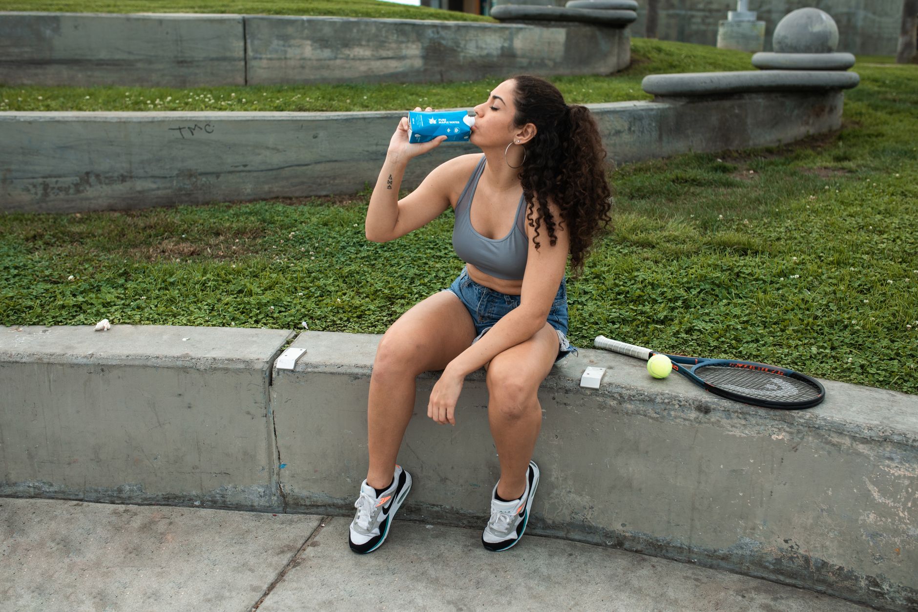 pregnant woman drinking water during a tennis break
