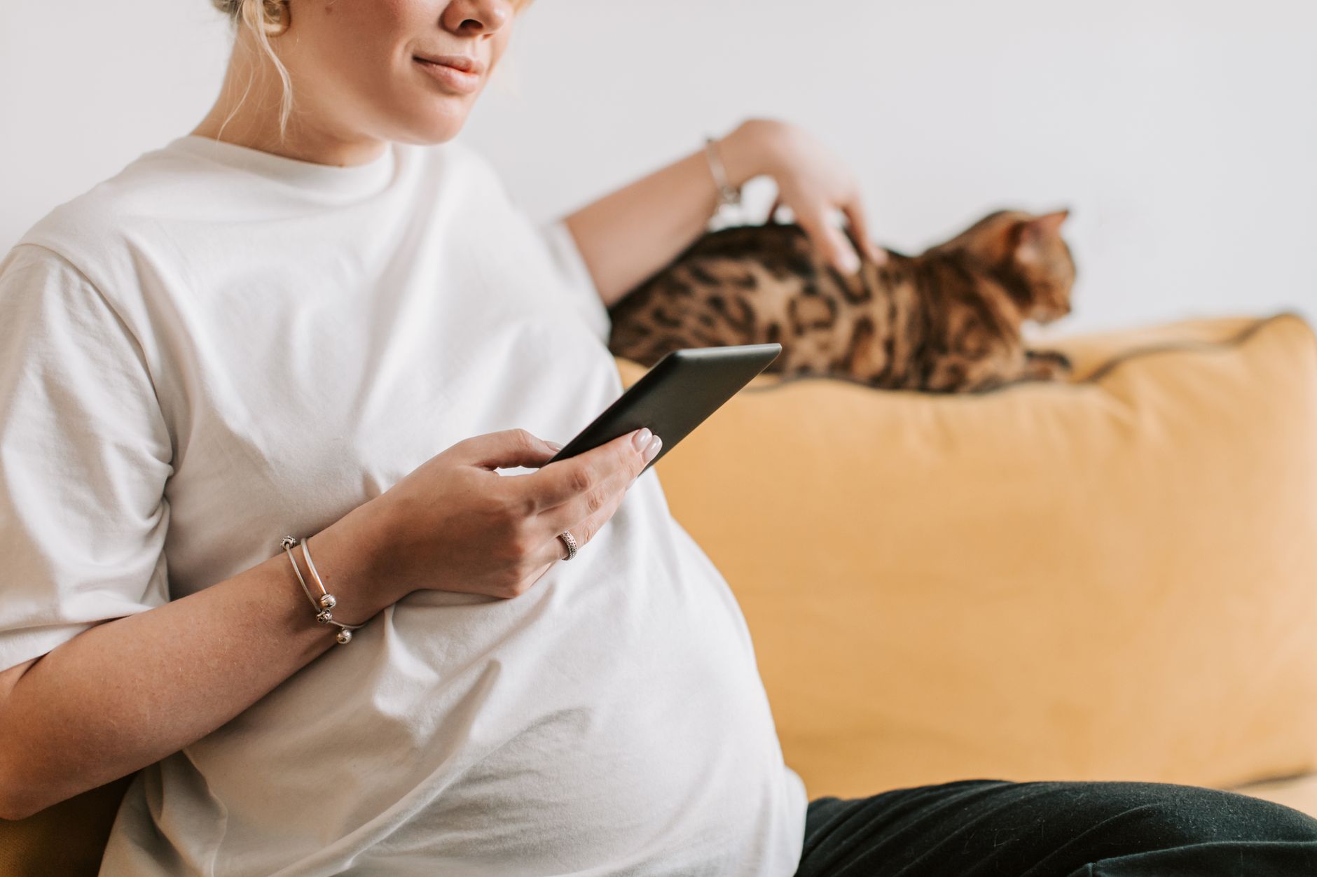 a pregnant woman checking her calendar and a flu vaccine reminder on a phone app, highlighting timing considerations for flu vaccination during pregnancy